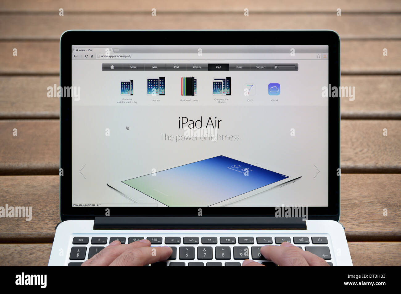 L'Apple iPad site sur un MacBook contre un banc en bois fond de plein air y compris les doigts d'un homme (usage éditorial uniquement). Banque D'Images