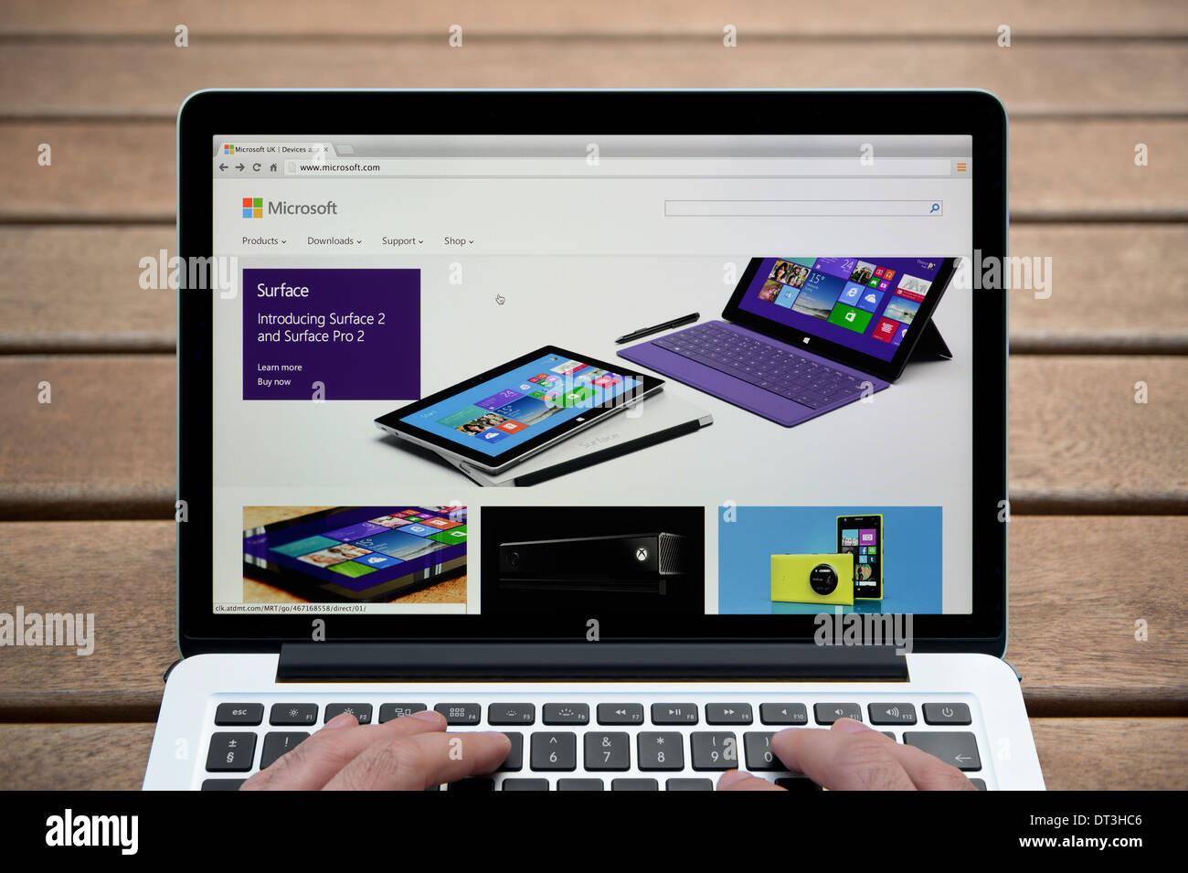 Le site Web de Microsoft sur un MacBook contre un banc en bois fond de plein air y compris les doigts d'un homme (usage éditorial uniquement). Banque D'Images