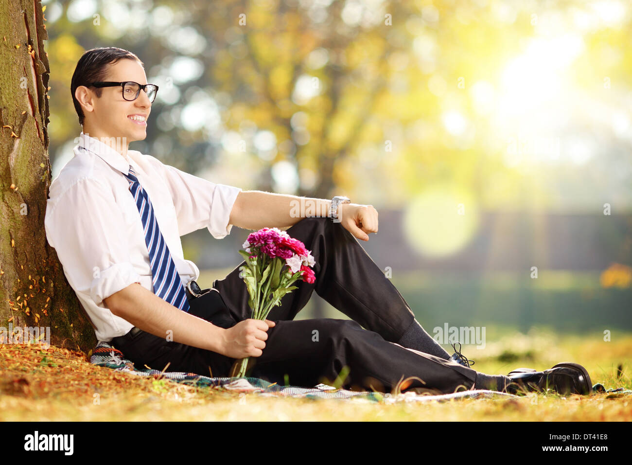 Beau mec avec un bouquet de fleurs dans le parc de détente sur une journée ensoleillée Banque D'Images