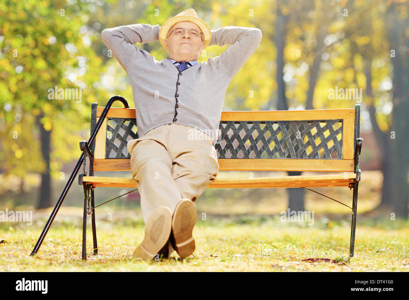 La haute atmosphère gentleman assis sur un banc dans un parc sur une journée ensoleillée Banque D'Images