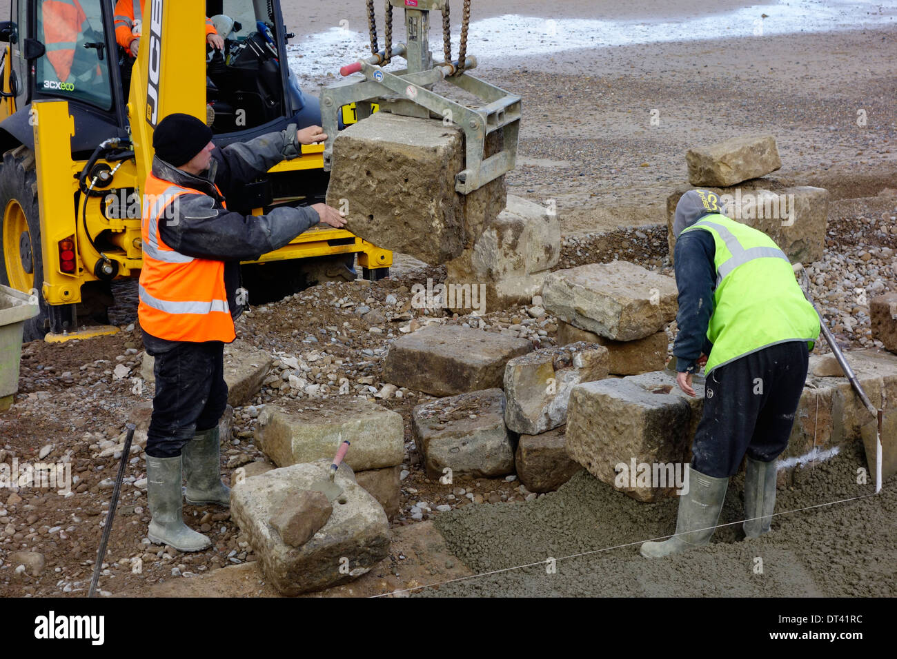 Placer un bloc de pierre au cours de la réparation de la promenade victorienne Saltburn Stone d'être reconstruit après la tempête Banque D'Images