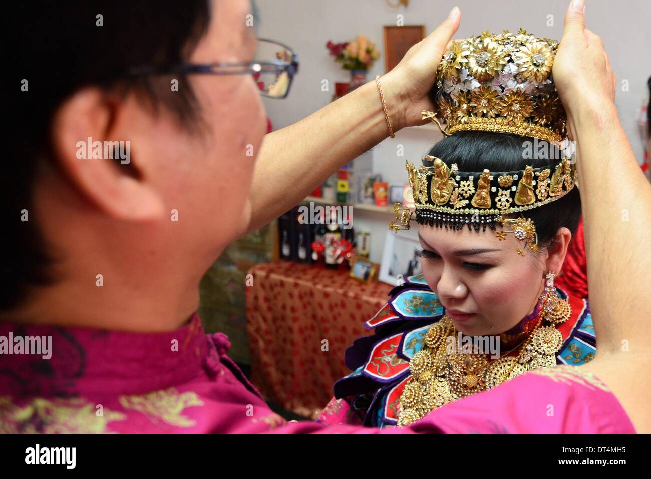 Melaka, Malaisie. Feb 8, 2014. Une cérémonie de mariage Baba Nyonya ajuste l'hôte la couronne pour la mariée à Melaka, Malaisie, le 8 février, 2014. Le baba Nyonya (ou Peranakan) est une communauté minoritaire vivant dans le détroit de Malacca. Baba Nyonya désigne les hommes et les femmes signifie. Ils sont des descendants de la 15e et 16e siècle, les immigrants chinois qui sont venus ici en tant que commerçants avant l'époque coloniale, s'est installé dans l'archipel malais et adaptés à la langue et la culture locale. © Chong Chung Voon/Xinhua/Alamy Live News Banque D'Images