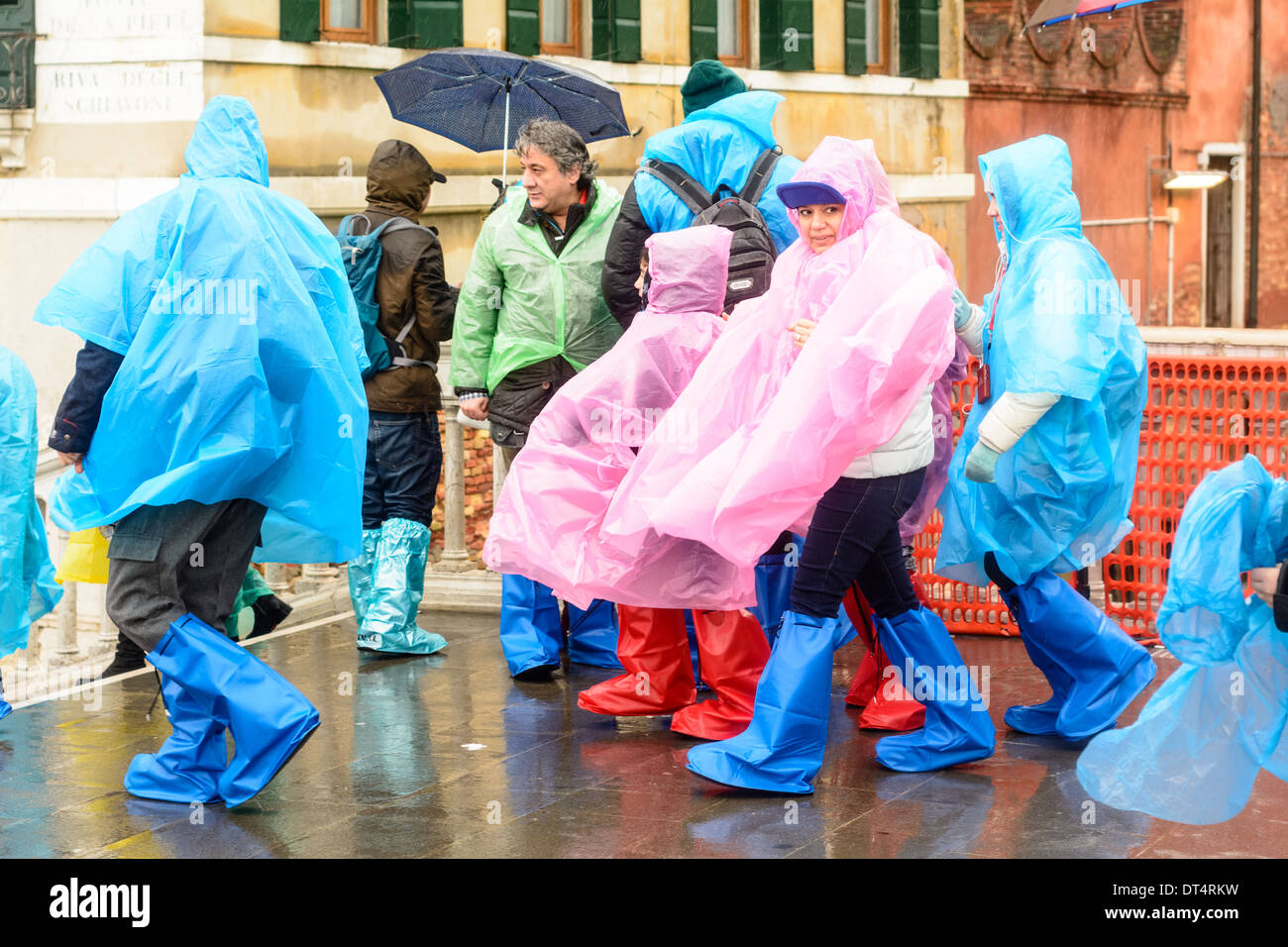 Venise, Italie. Les gens par temps humide, la pluie vêtements, ponchos et des bottes de pluie, debout sur le pont pendant la pluie. Banque D'Images