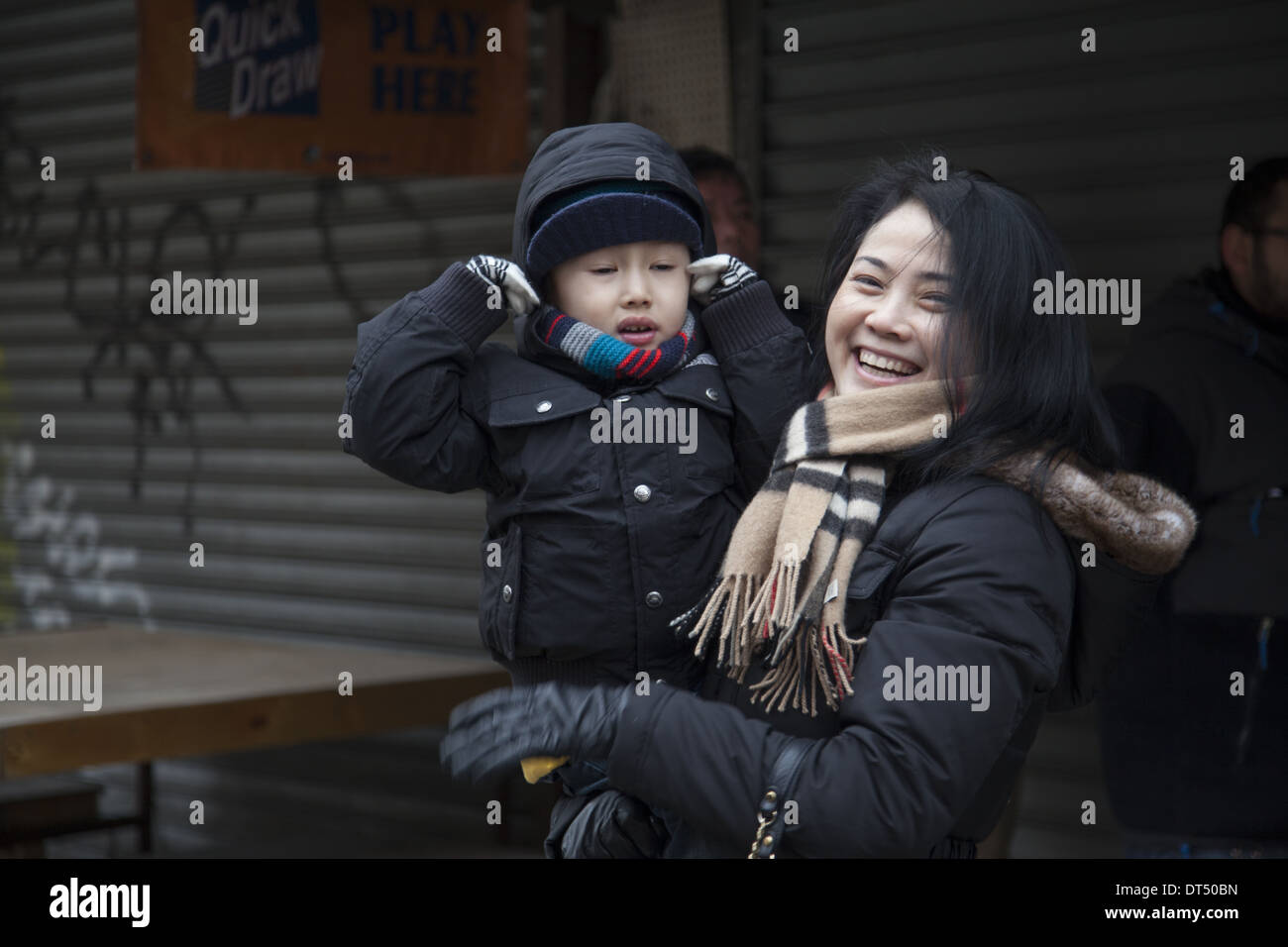 Mère avec son holding ses oreilles pendant le Nouvel An chinois cérémonie pétard dans Chinatown, NEW YORK. 2014, année du cheval. Banque D'Images