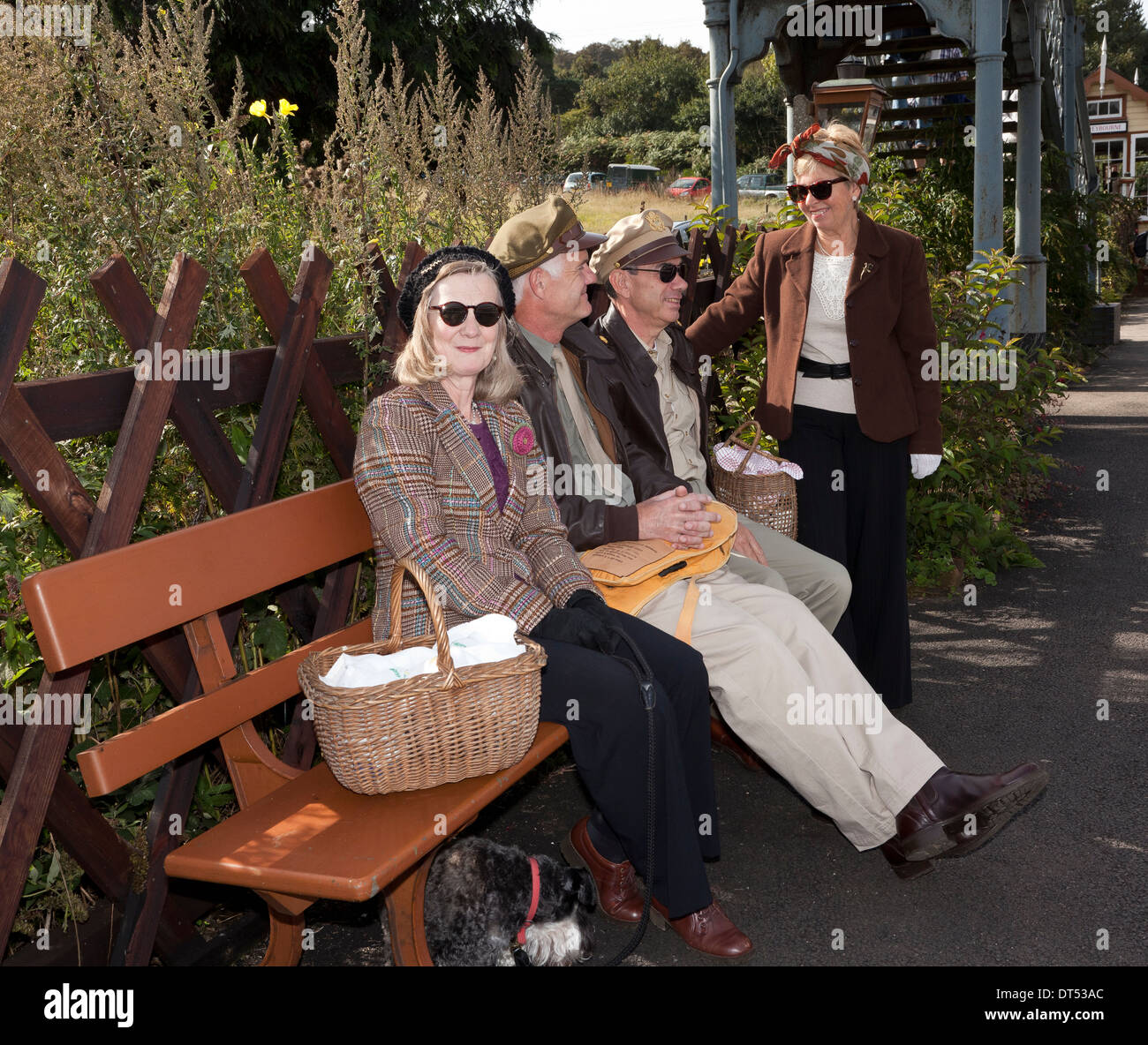 Quatre personnes en costume des années 1940, l'attente dans une gare ferroviaire UK Banque D'Images