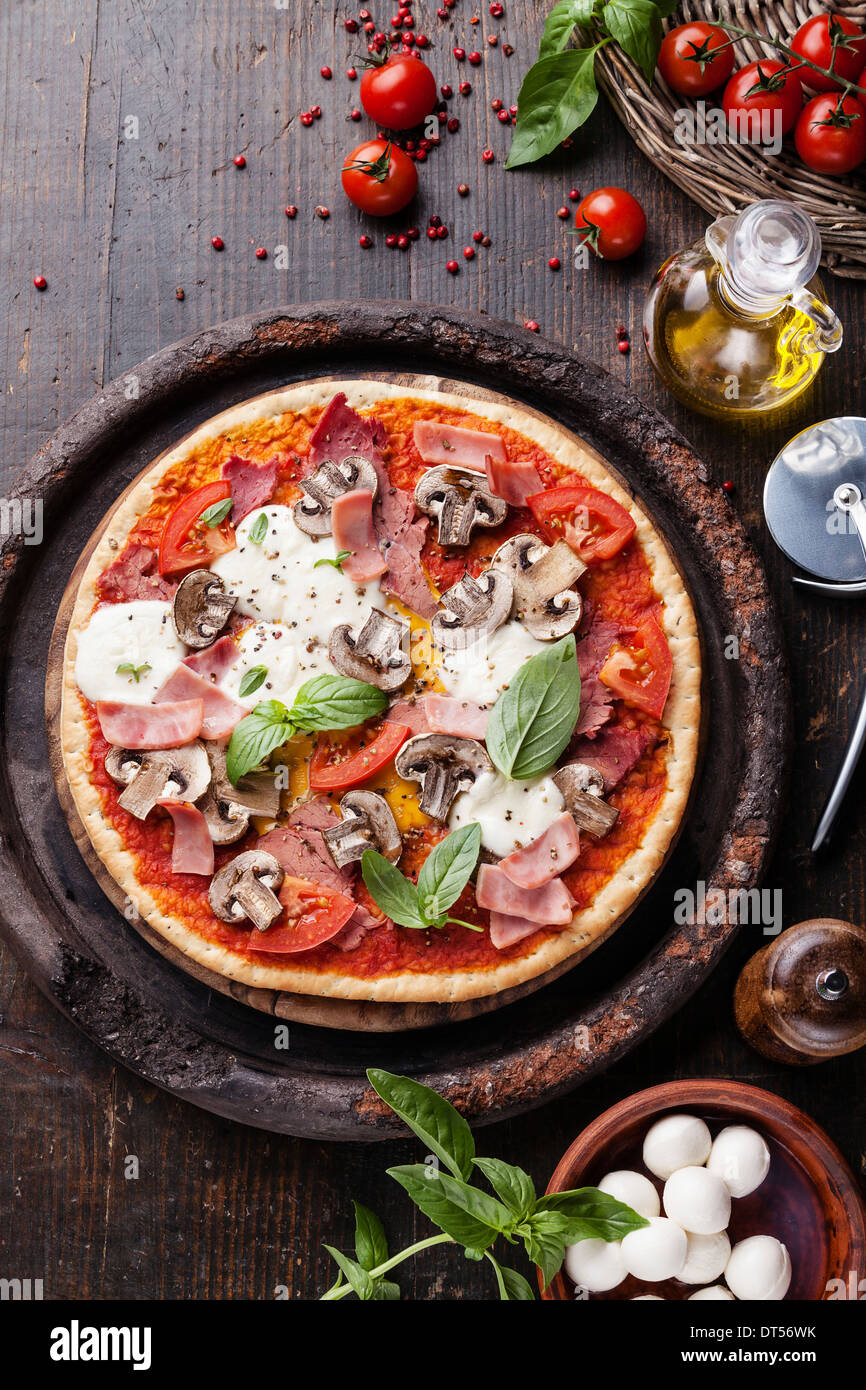 Pizza italienne avec de la viande, du jambon et des champignons sur table en bois Banque D'Images