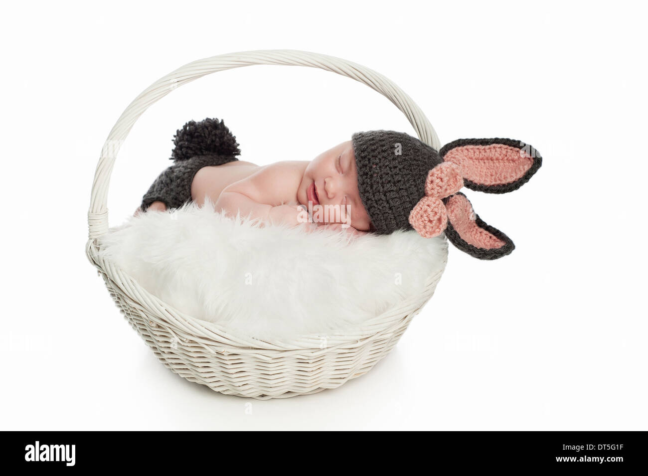 Sourire petite fille dormir dans un panier et portant un costume de lapin. Banque D'Images