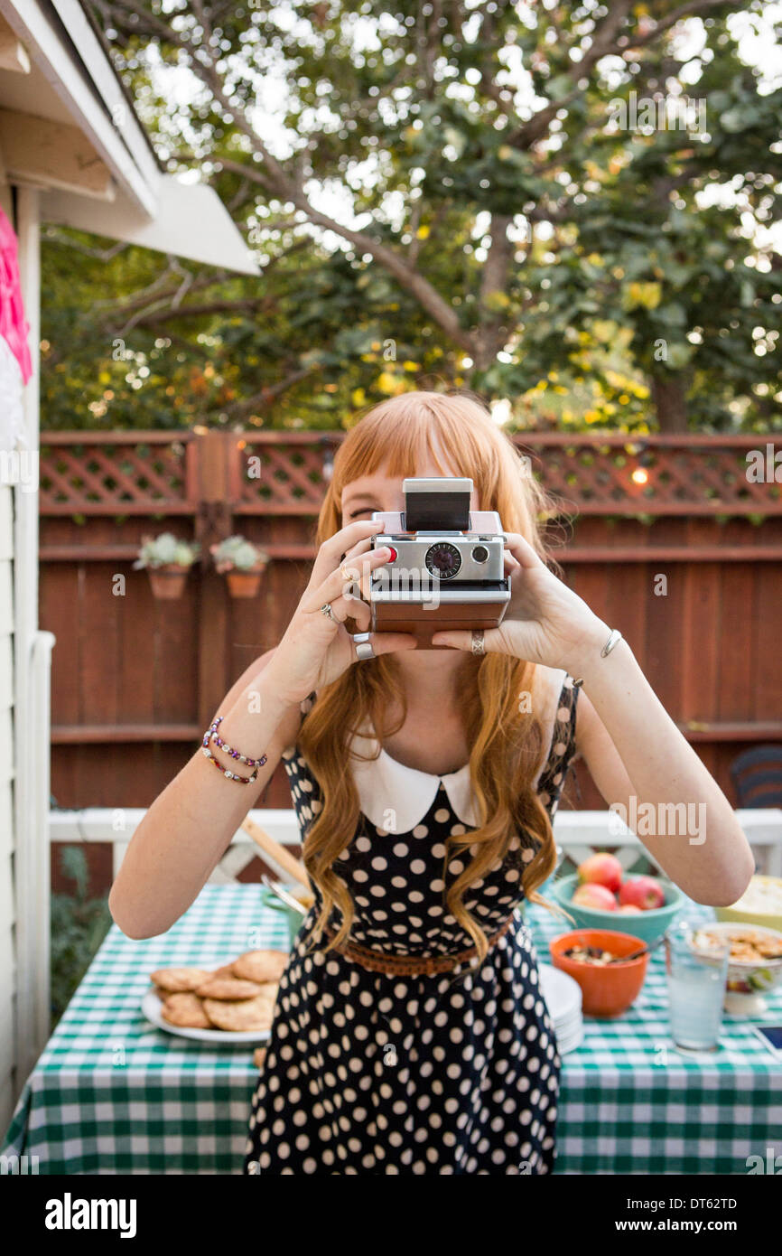 Jeune femme photographiant avec un appareil polaroid Banque D'Images