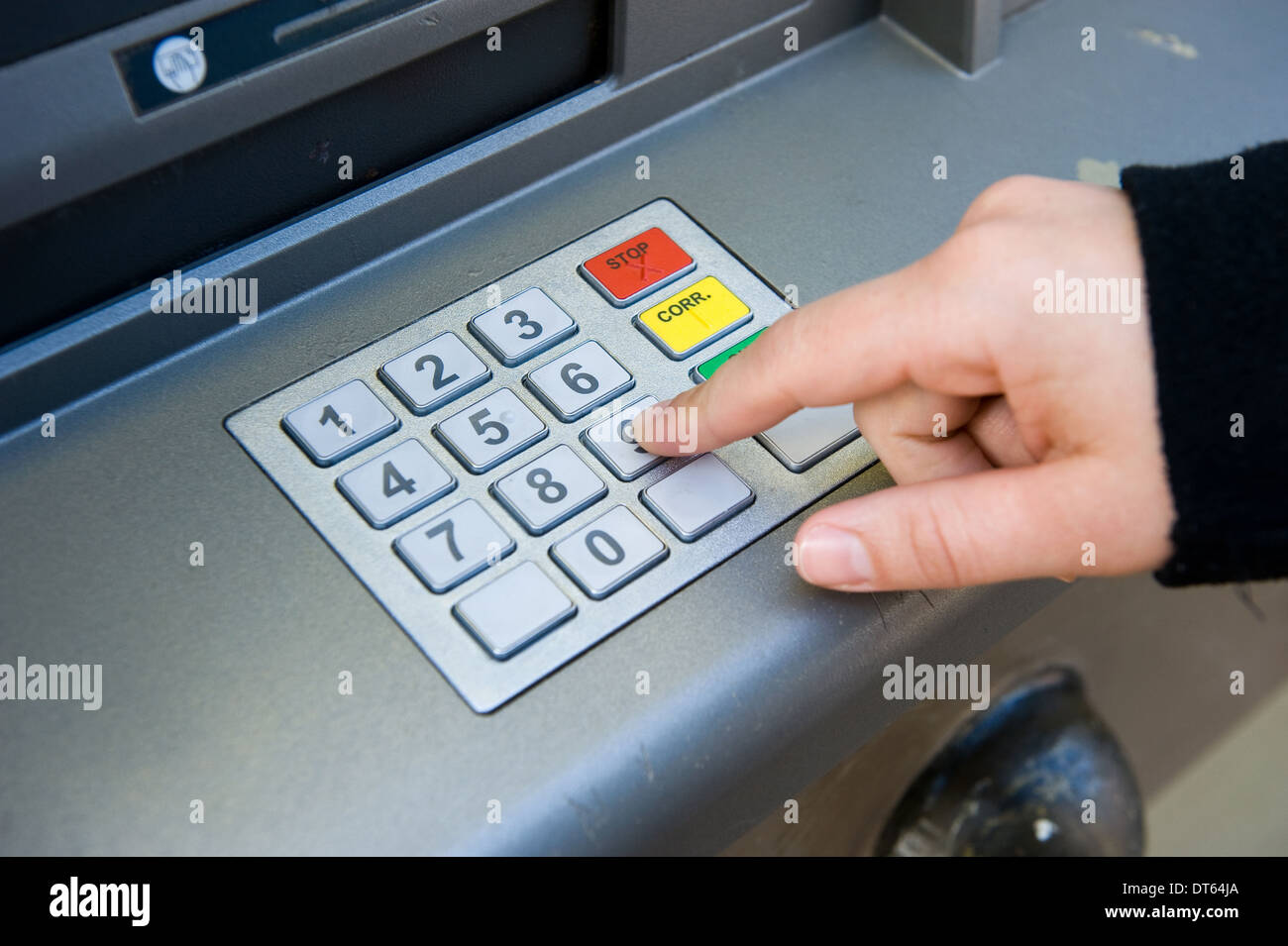 Une femme utilise son code d'accès pour obtenir l'argent comptant l'argent d'un guichet automatique Banque D'Images