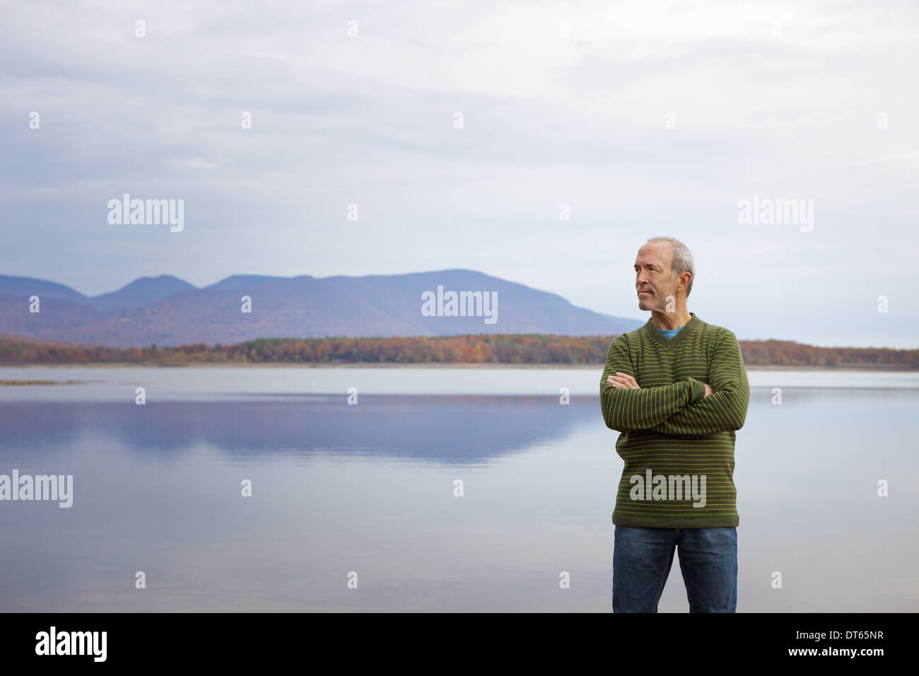 Un homme avec des bras pliés par l'eau d'un lac calme dans les montagnes. Banque D'Images