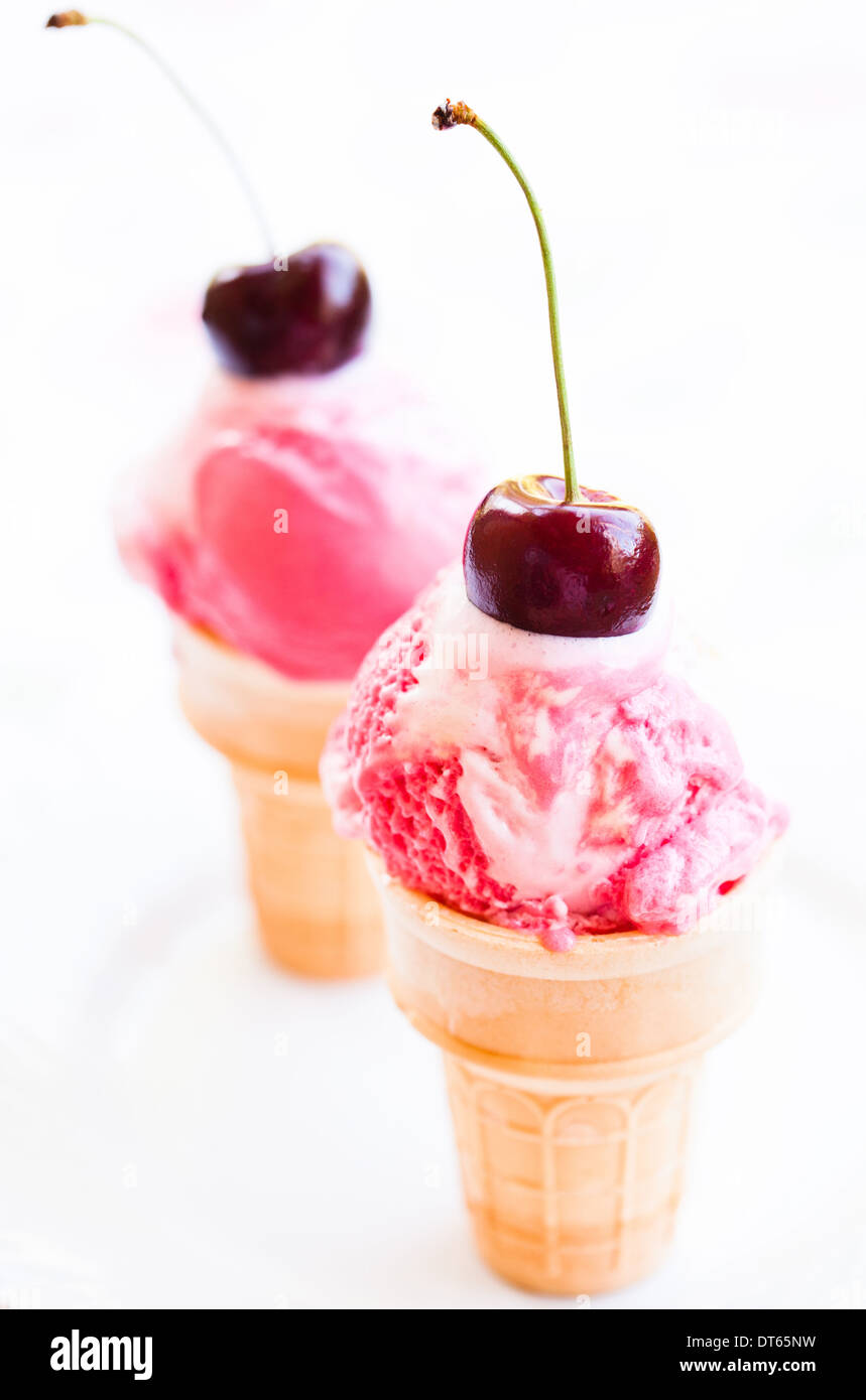 Libre de deux cônes de framboise et crème glacée à la vanille avec cherry décorations sur fond clair Banque D'Images