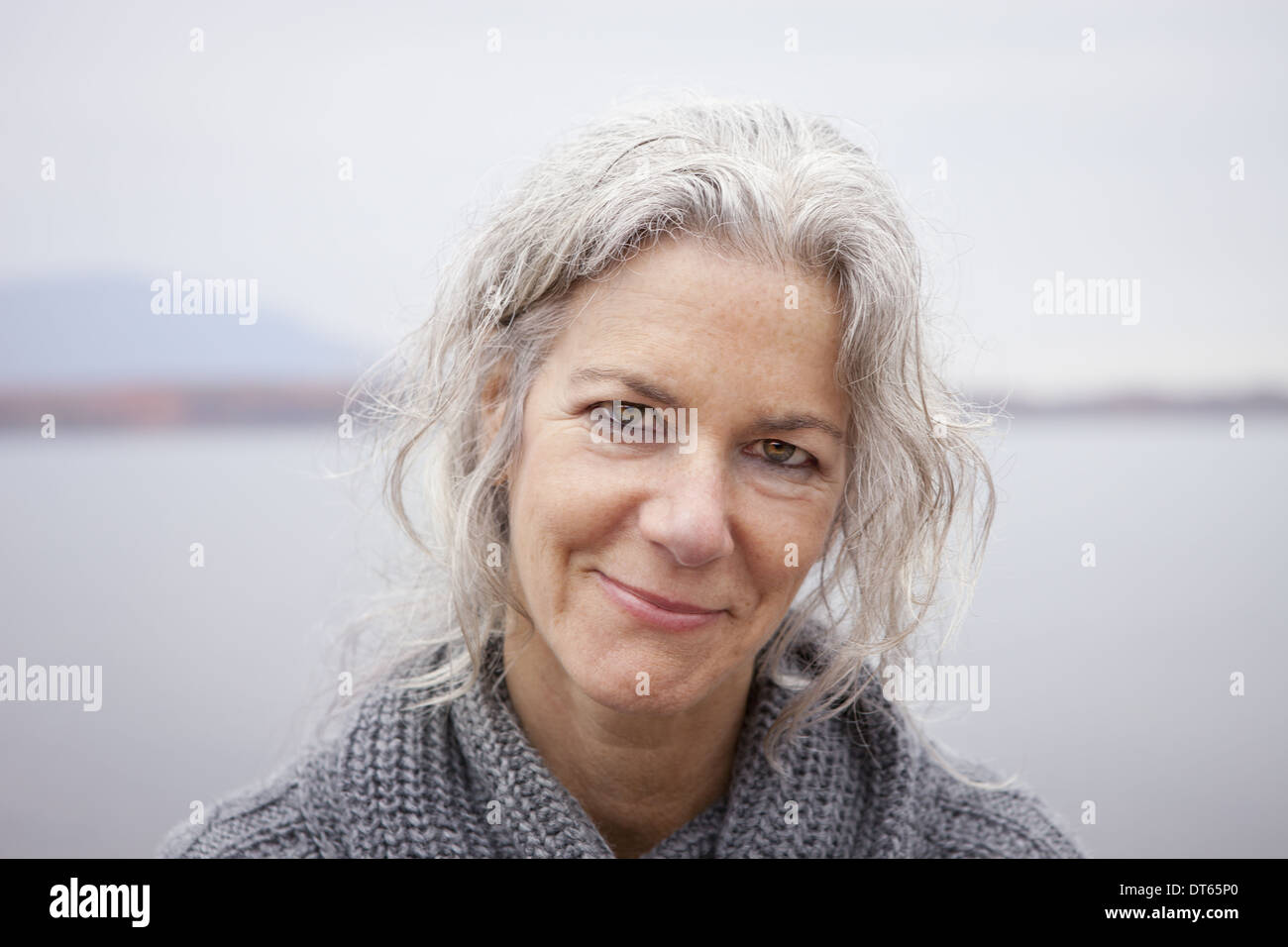 Une femme regardant la caméra, par le bord d'un lac. Banque D'Images