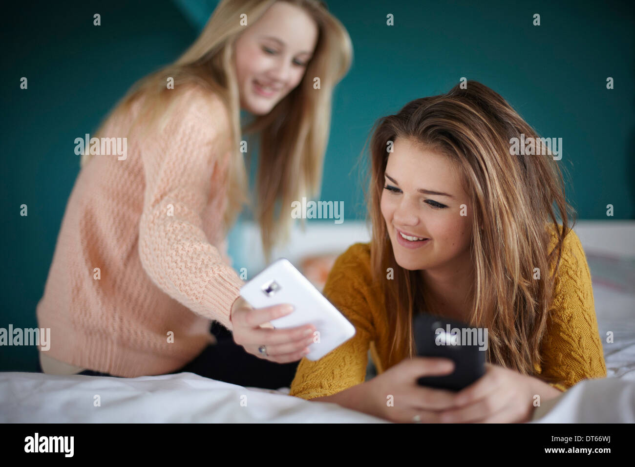 Deux teenage girls looking at smartphones en chambre Banque D'Images