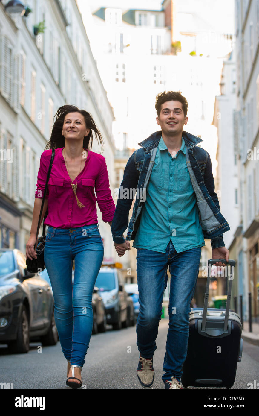 Jeune couple avec valise à roulettes, Paris, France Banque D'Images