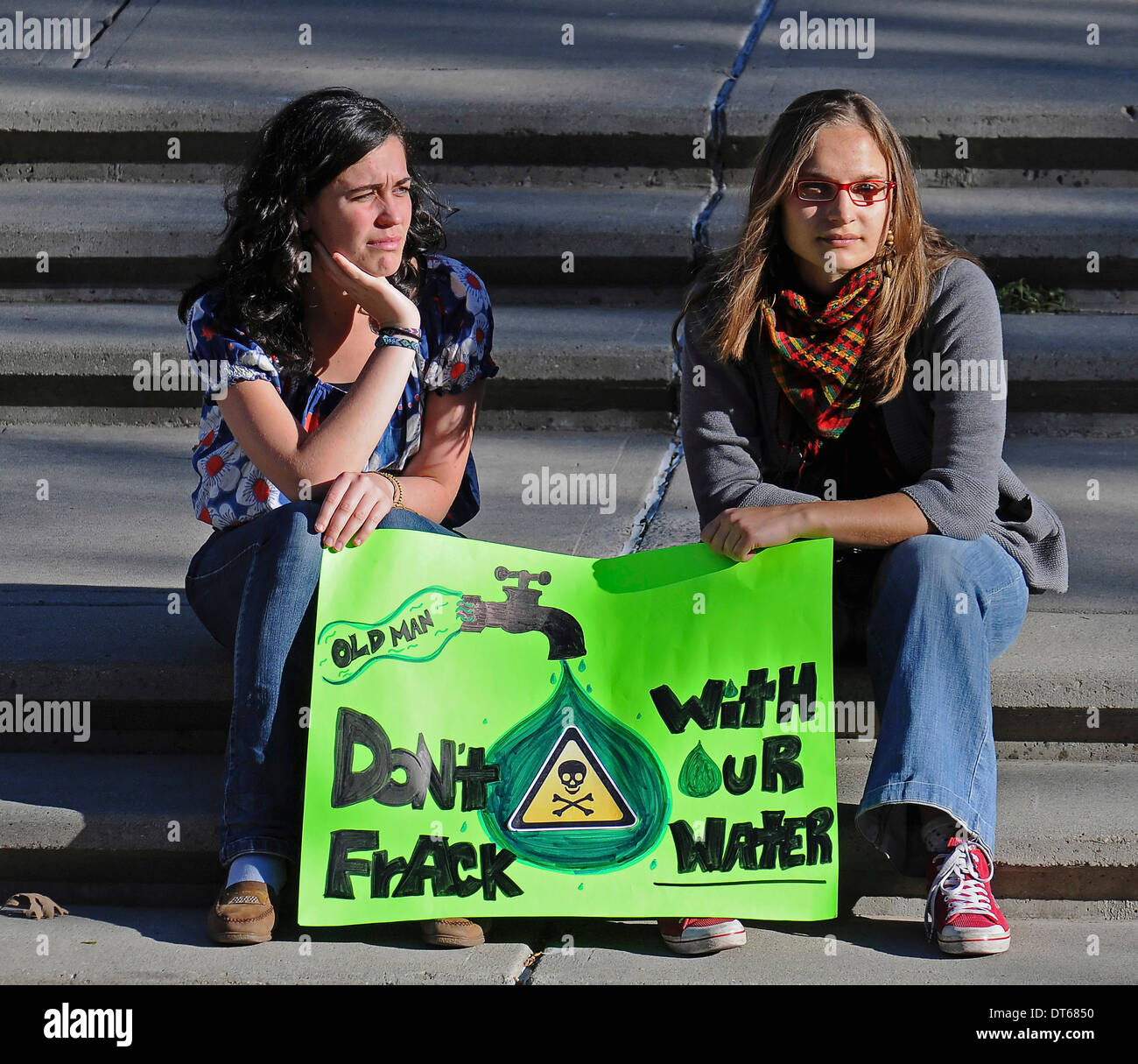 Le Canada, l'Alberta, Lethbridge, deux femmes locales atsitting sur marches de pierre à une démonstration de fracturation holding a placard. Banque D'Images