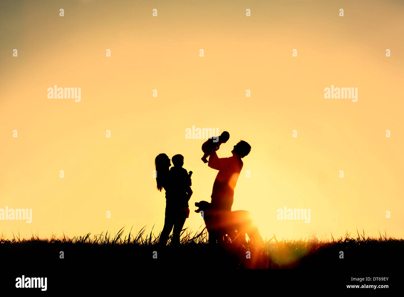 La silhouette d'une famille heureuse de quatre personnes, le père, la mère, un bébé et enfant, et de leur chien en face d'un ciel temporaire, Banque D'Images