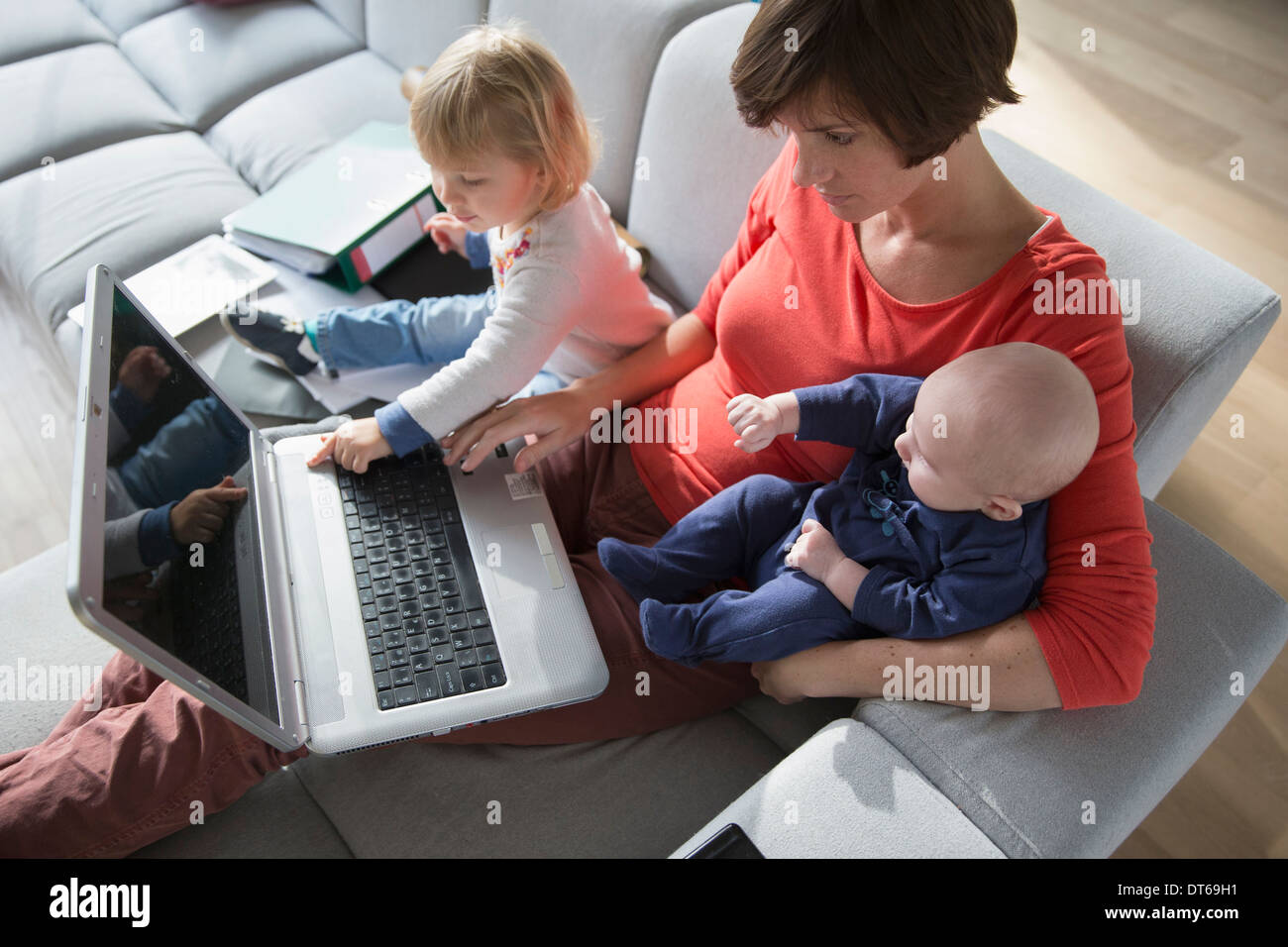 Bébé garçon, mère et enfant de sexe féminin à l'aide de l'ordinateur portable sur canapé Banque D'Images