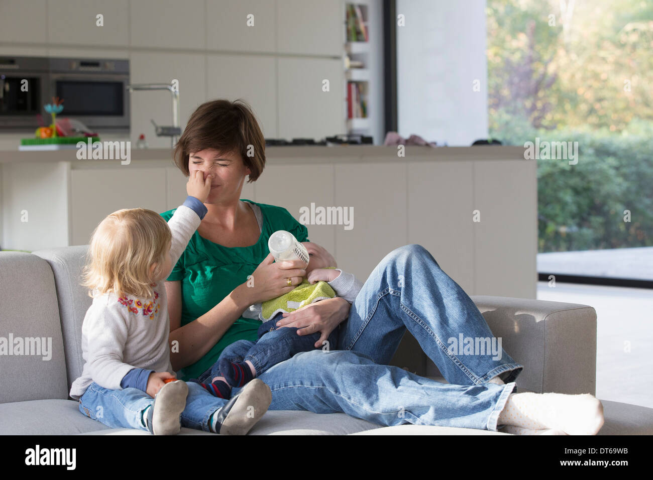 Mère, baby boy and female toddler sitting on sofa Banque D'Images