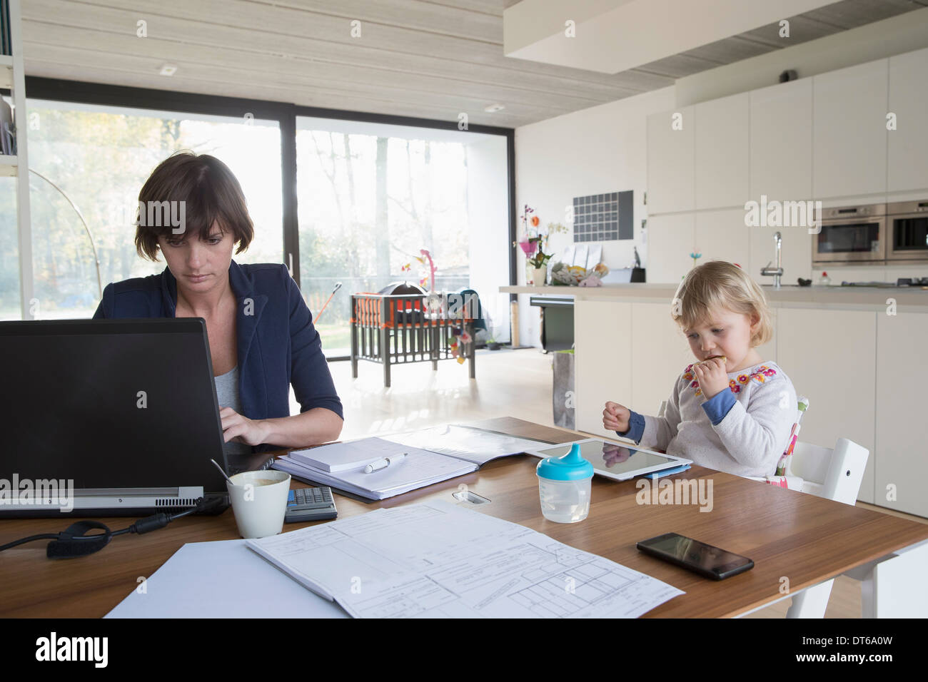 Mère avec enfant de sexe féminin travaillant sur ordinateur à la table de  cuisine Photo Stock - Alamy