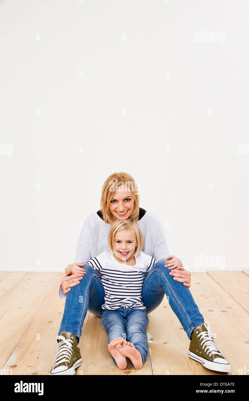 Studio Portrait of mother and daughter sitting on floor Banque D'Images