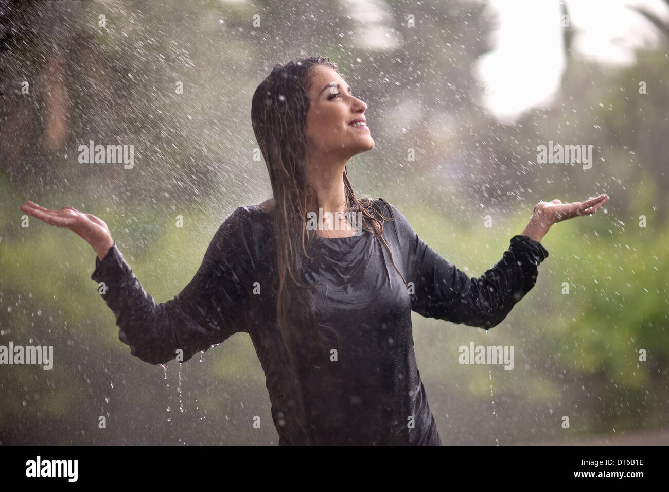 Jeune femme au soleil avec les bras ouverts dans rainy park Banque D'Images