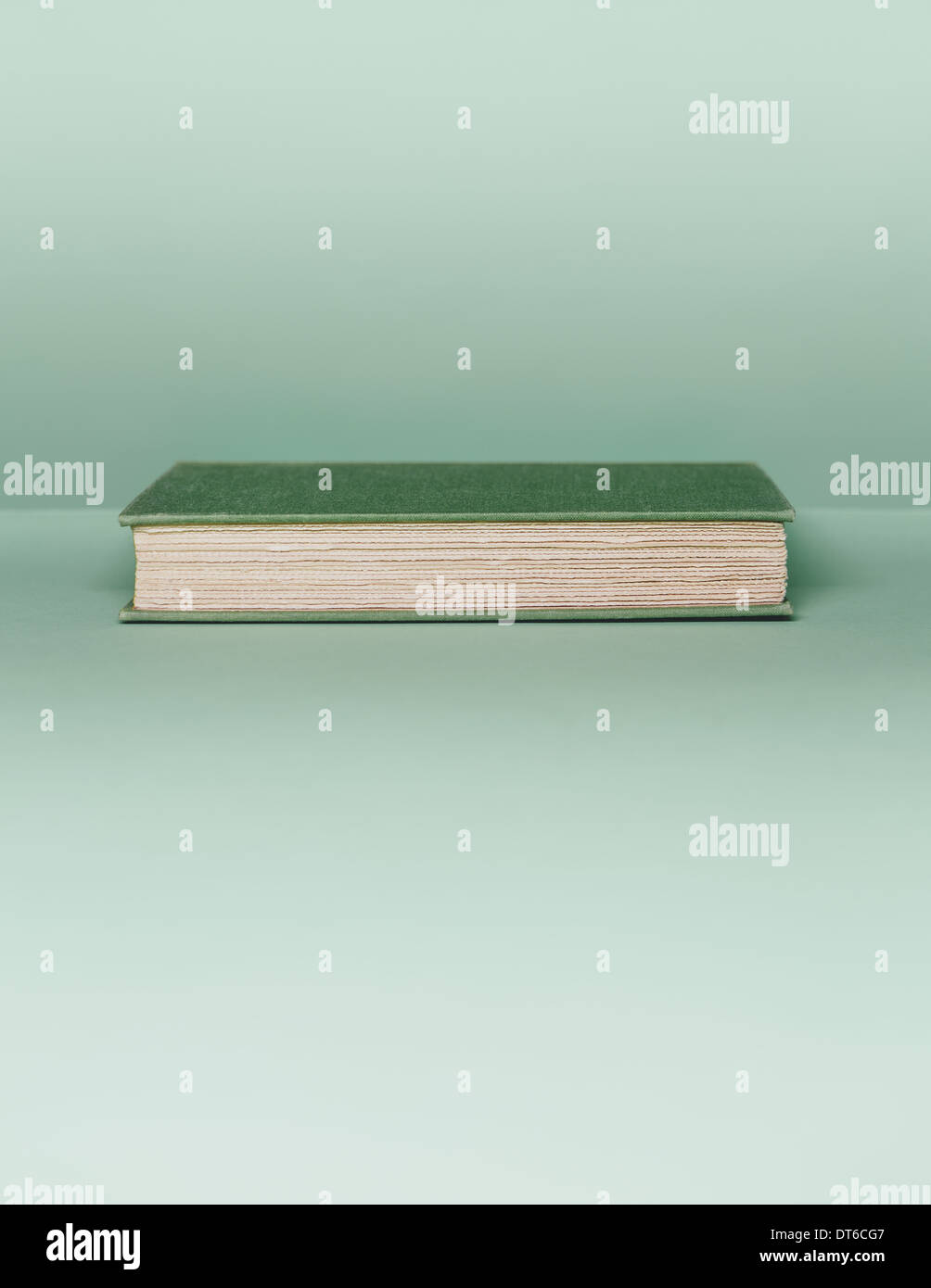 Un livre avec une couverture verte, et le livre blanc, les bords de la page située à l'horizontale sur un fond vert pâle. Banque D'Images