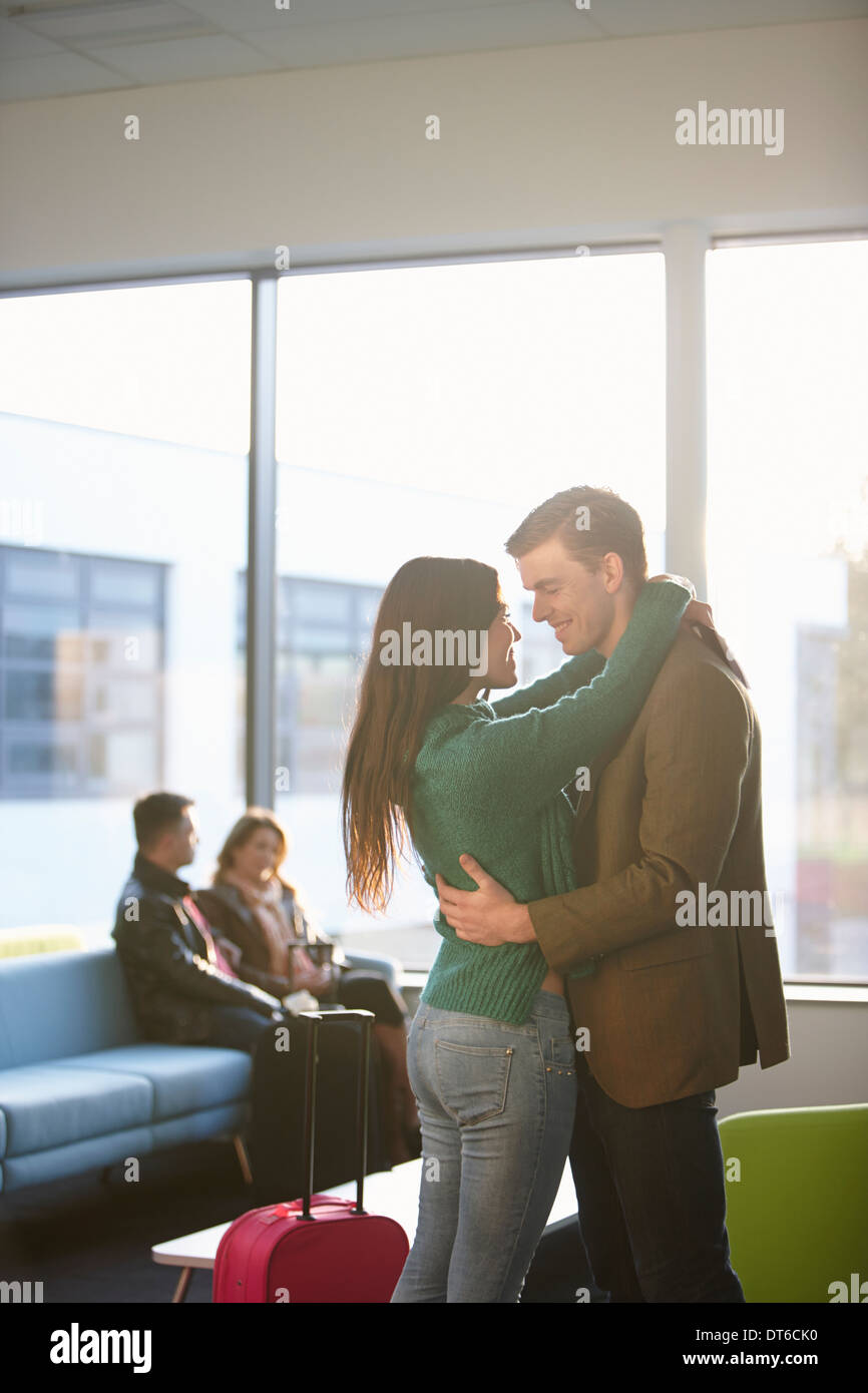 Jeune couple hugging in airport Banque D'Images