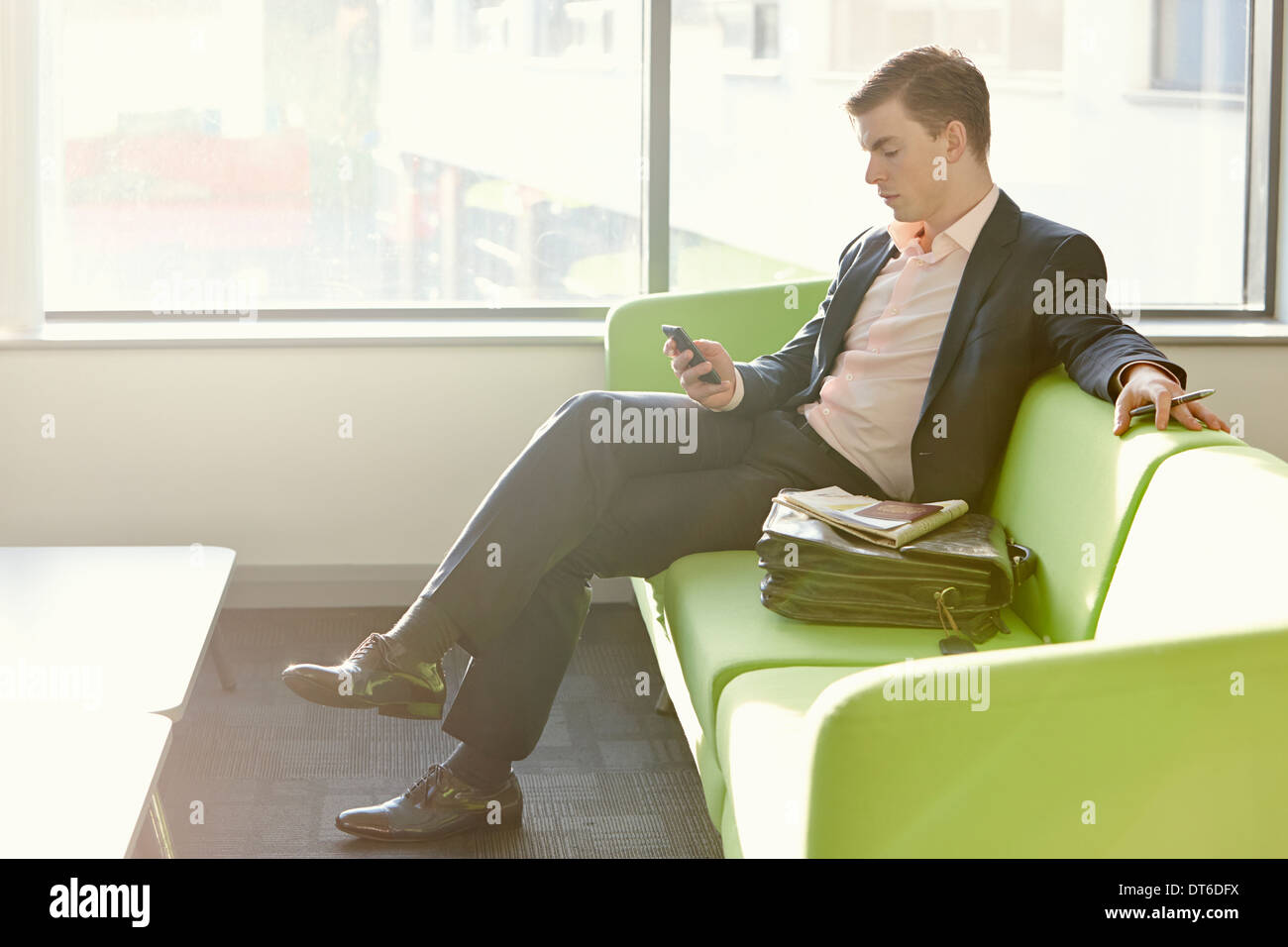 Businessman in departure lounge using cell phone Banque D'Images