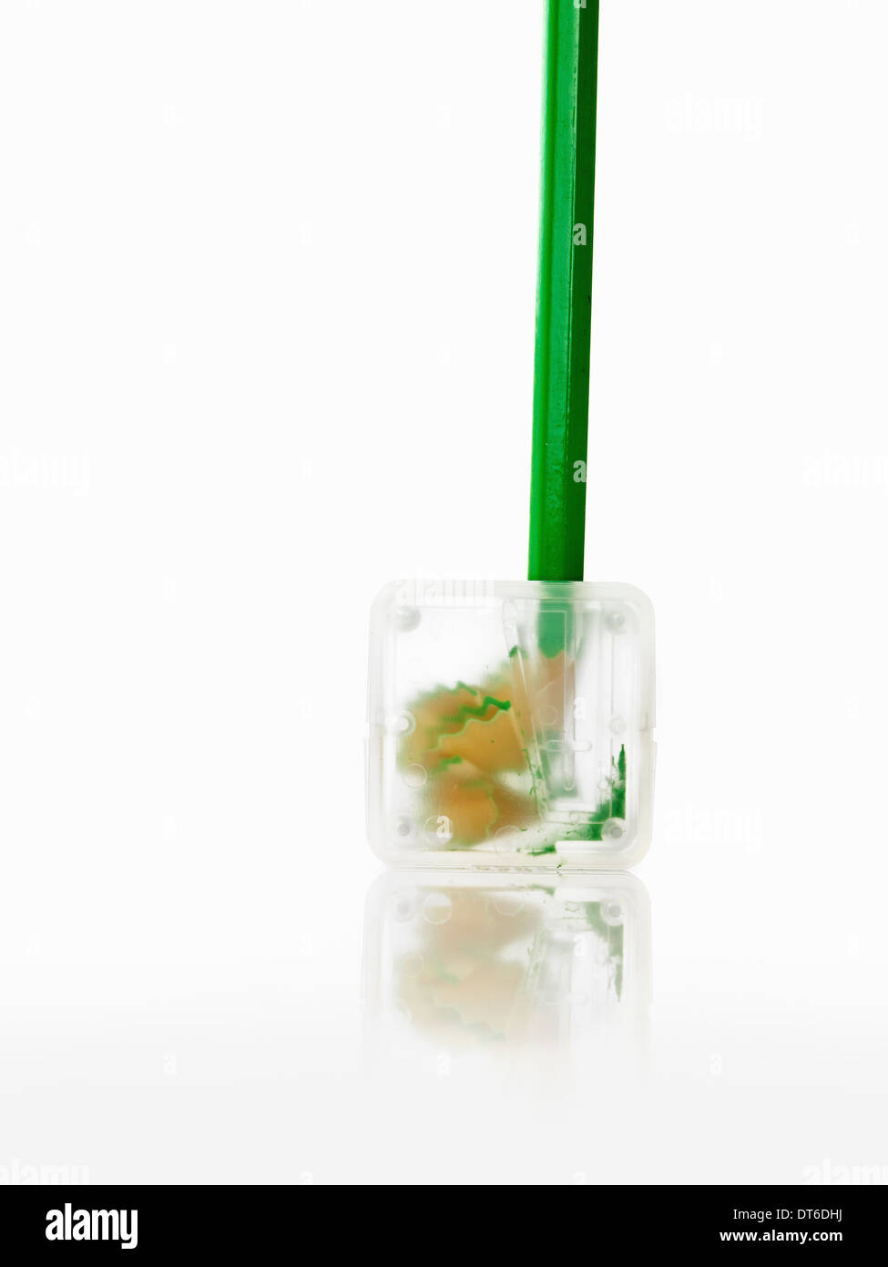 Crayon vert et un taille-crayon en plastique transparent. Banque D'Images