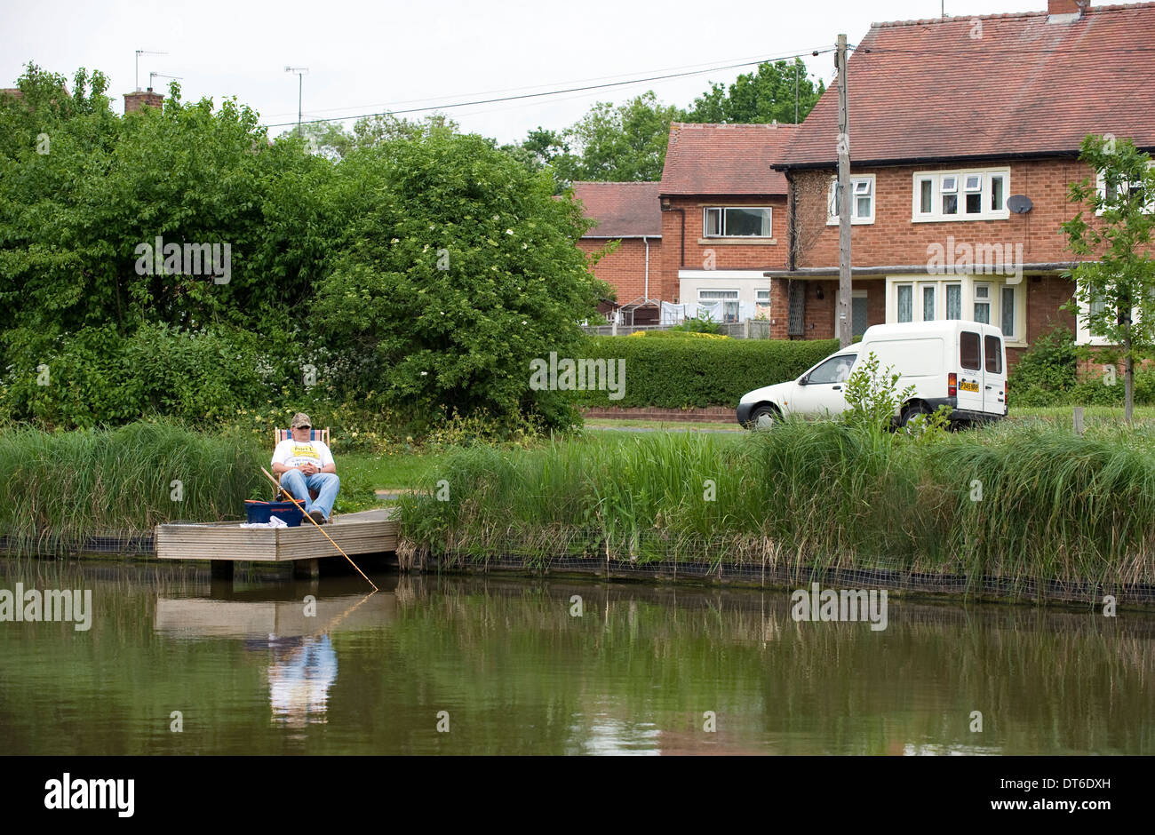 Un pêcheur et relaxant à un étang de pêche dans un emplacement urbain, Redditch, Worcestershire. Banque D'Images