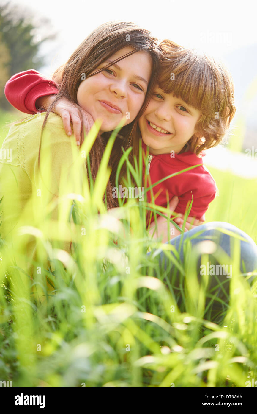 Soeur et frère cadet sitting in grassy field Banque D'Images