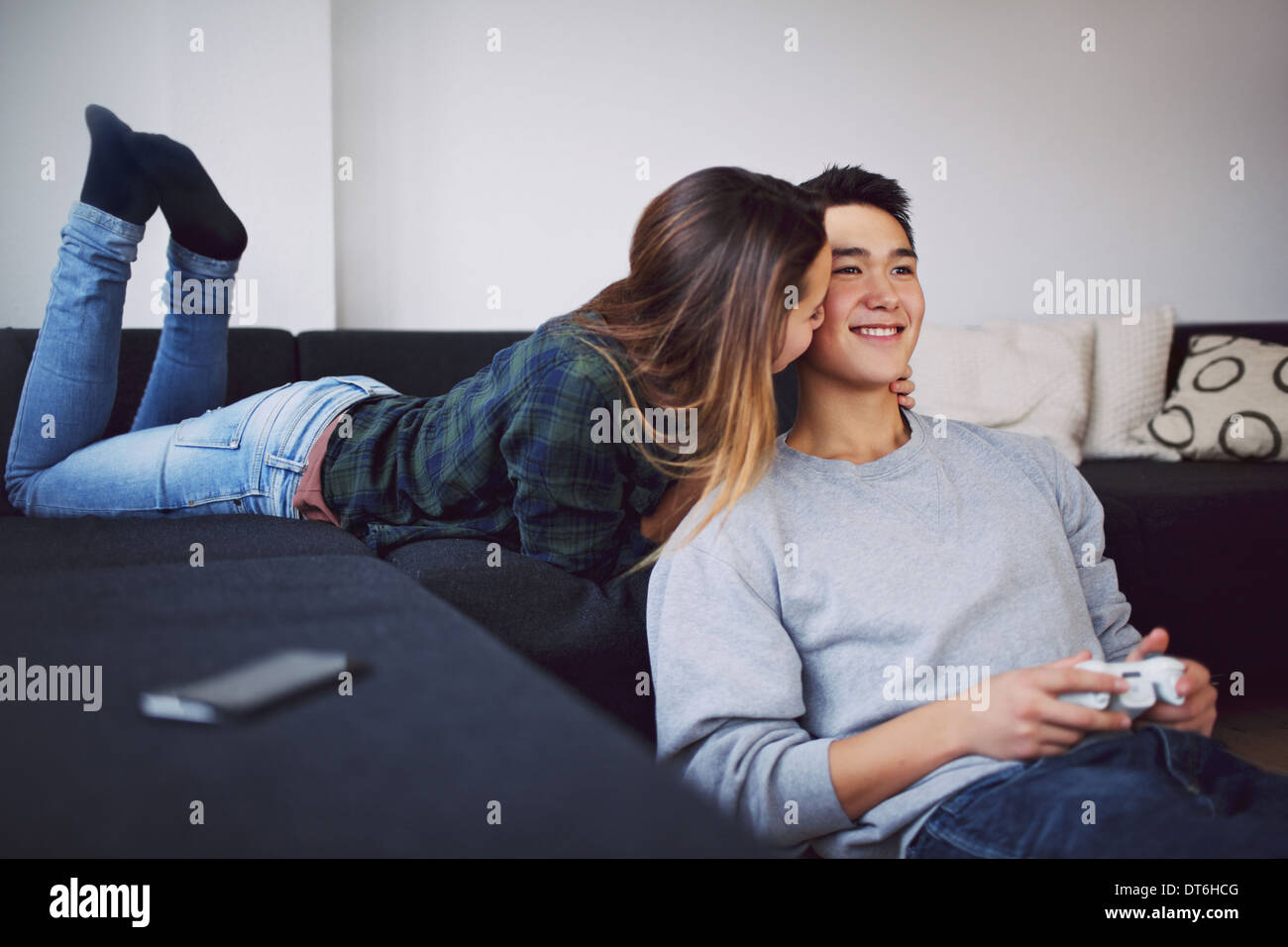 Couple dans la salle de séjour. Belle femme prend soin de son petit ami de jouer un jeu vidéo. Banque D'Images