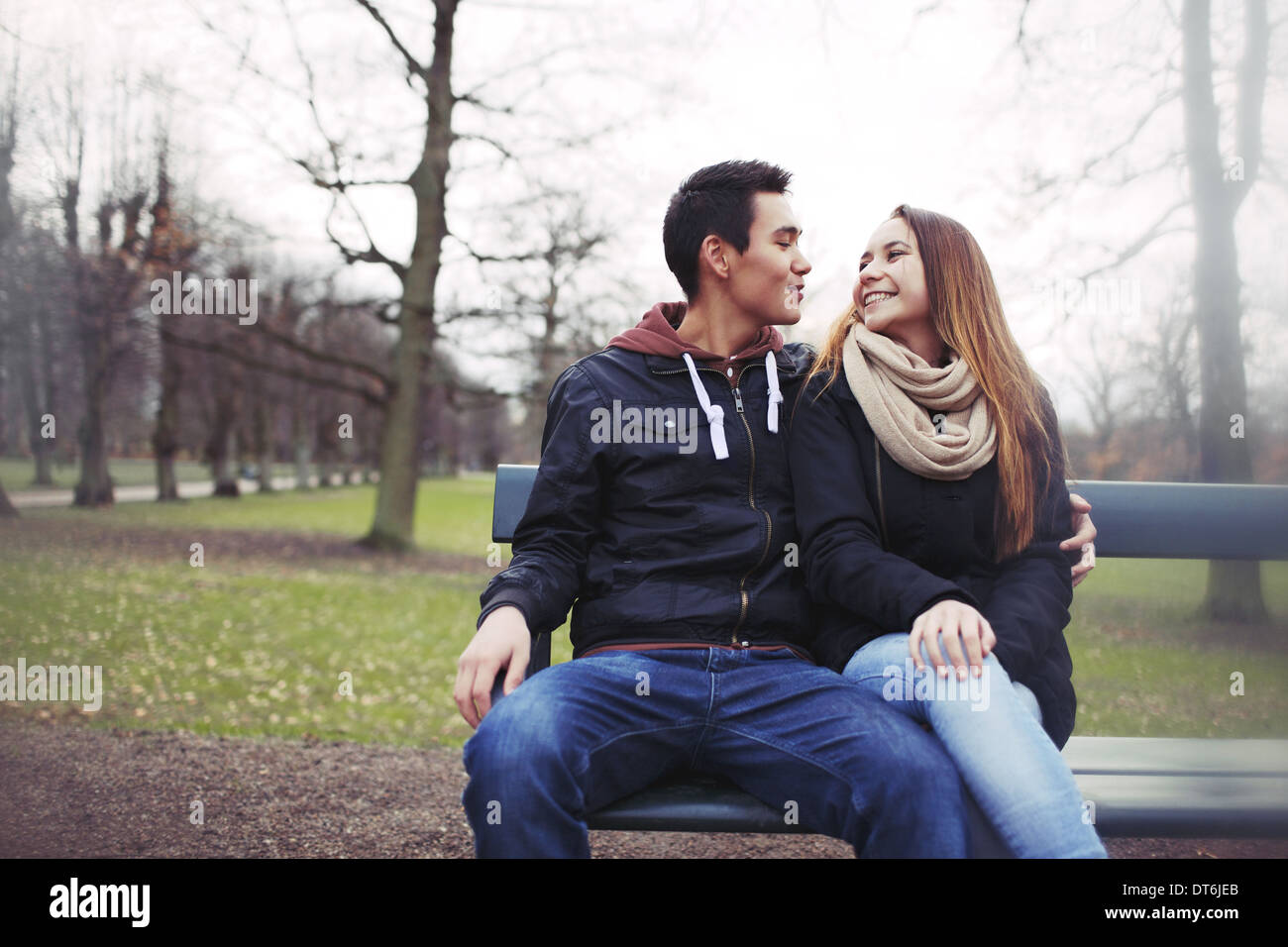 Couple assis sur un banc à l'extérieur pendant la saison d'hiver. Asian teenage couple dans des vêtements chauds assis sur banc de parc. Banque D'Images