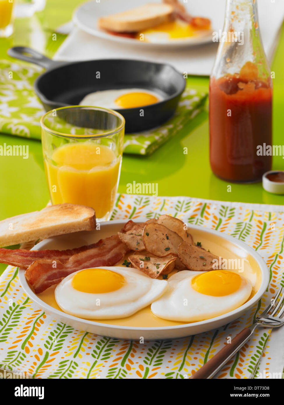 Une scène de petit-déjeuner avec Sunny Side Up œufs, bacon, toasts, pommes de terre, petit-déjeuner et un verre de jus d'orange Banque D'Images