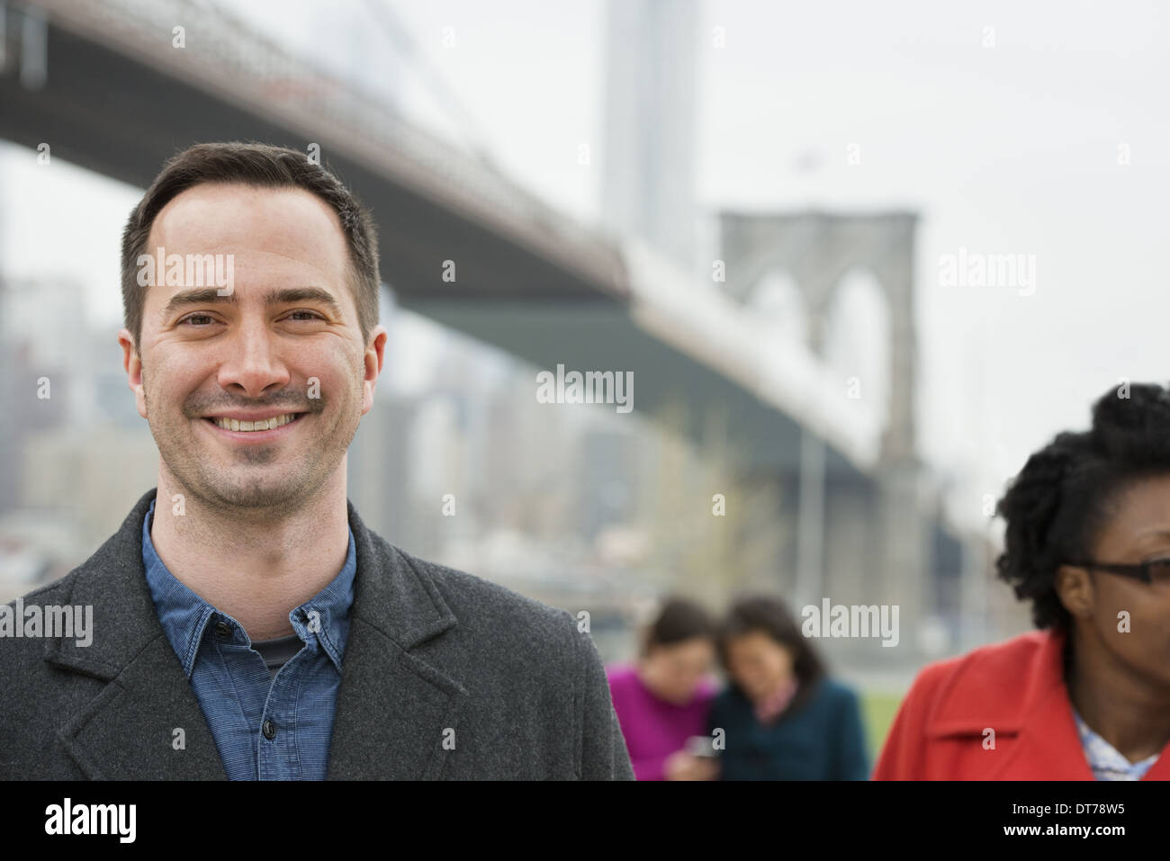 Passage sur la East River. Quatre personnes, deux femmes à la recherche à un téléphone intelligent, et un homme et une femme au premier plan. Banque D'Images