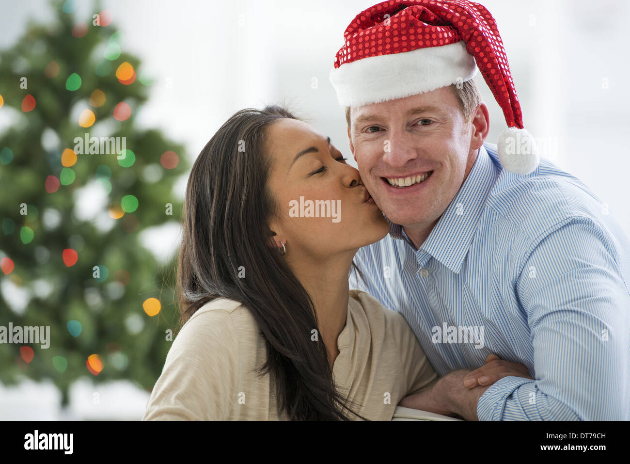 Un homme dans un chapeau de Père Noël. À la maison. Décoré d'un arbre de Noël. Banque D'Images