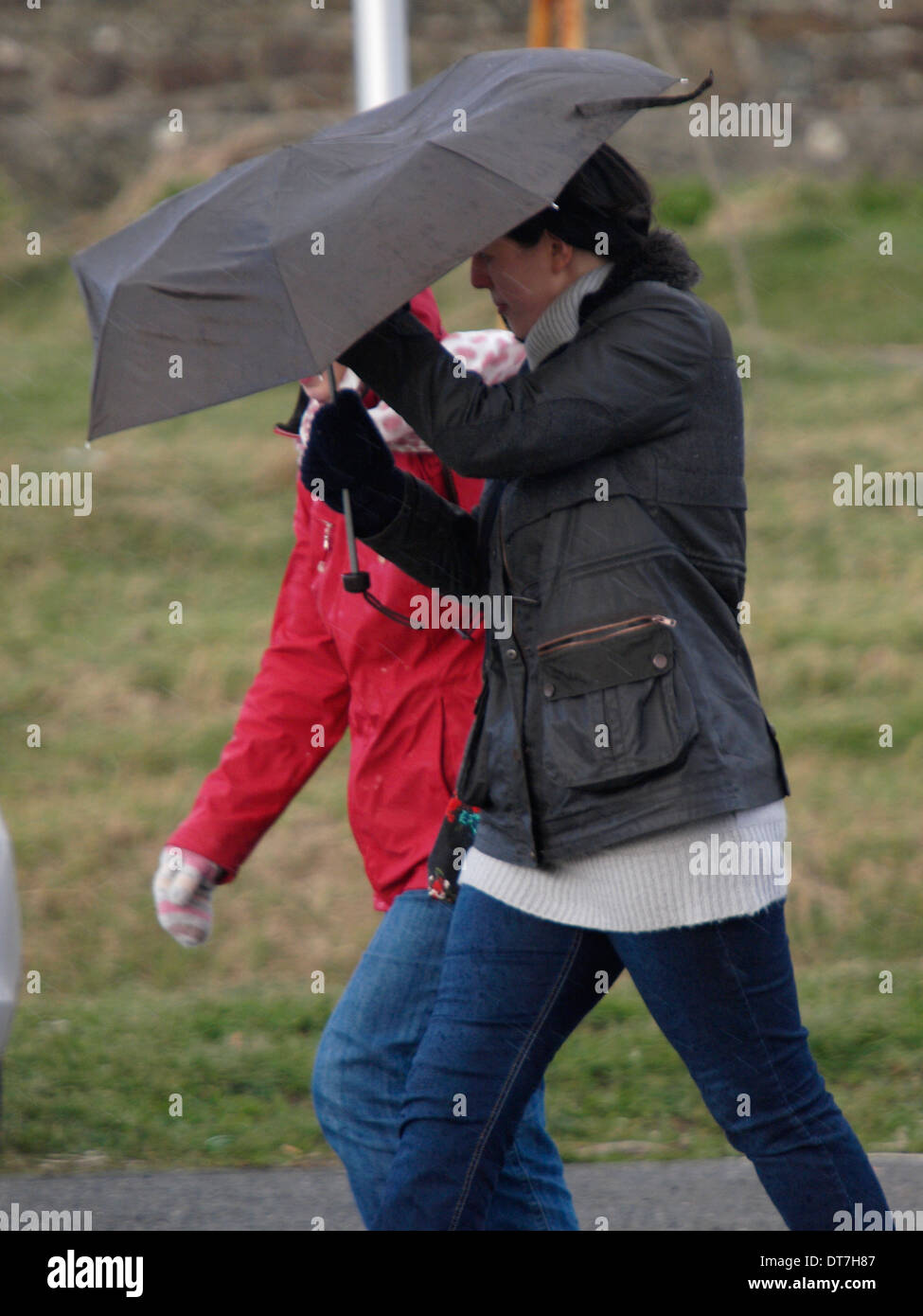 Femme aux prises avec un parapluie par temps venteux. Banque D'Images