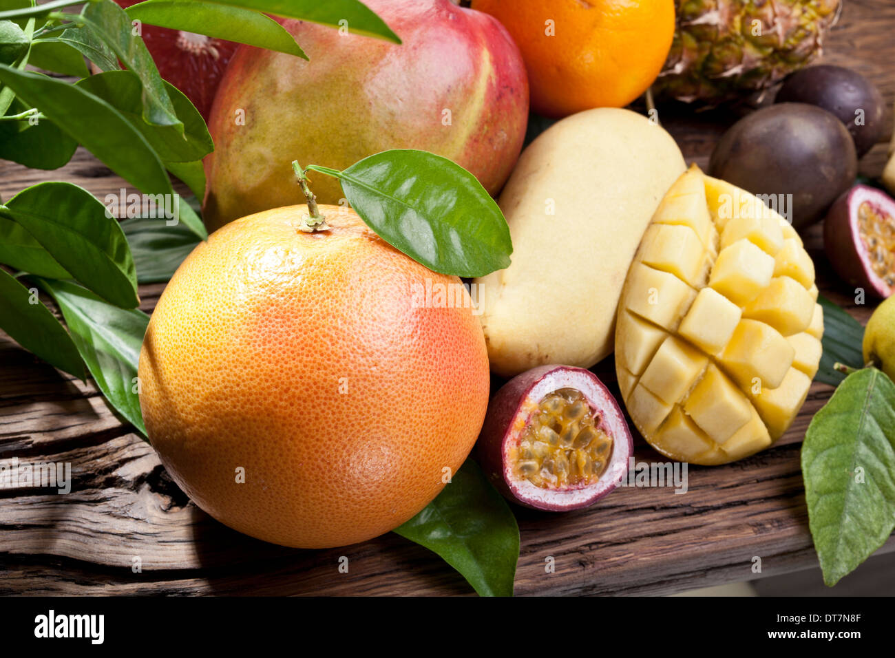 Fruits exotiques sur une table en bois avec feuillage vert sur l'arrière-plan. Banque D'Images