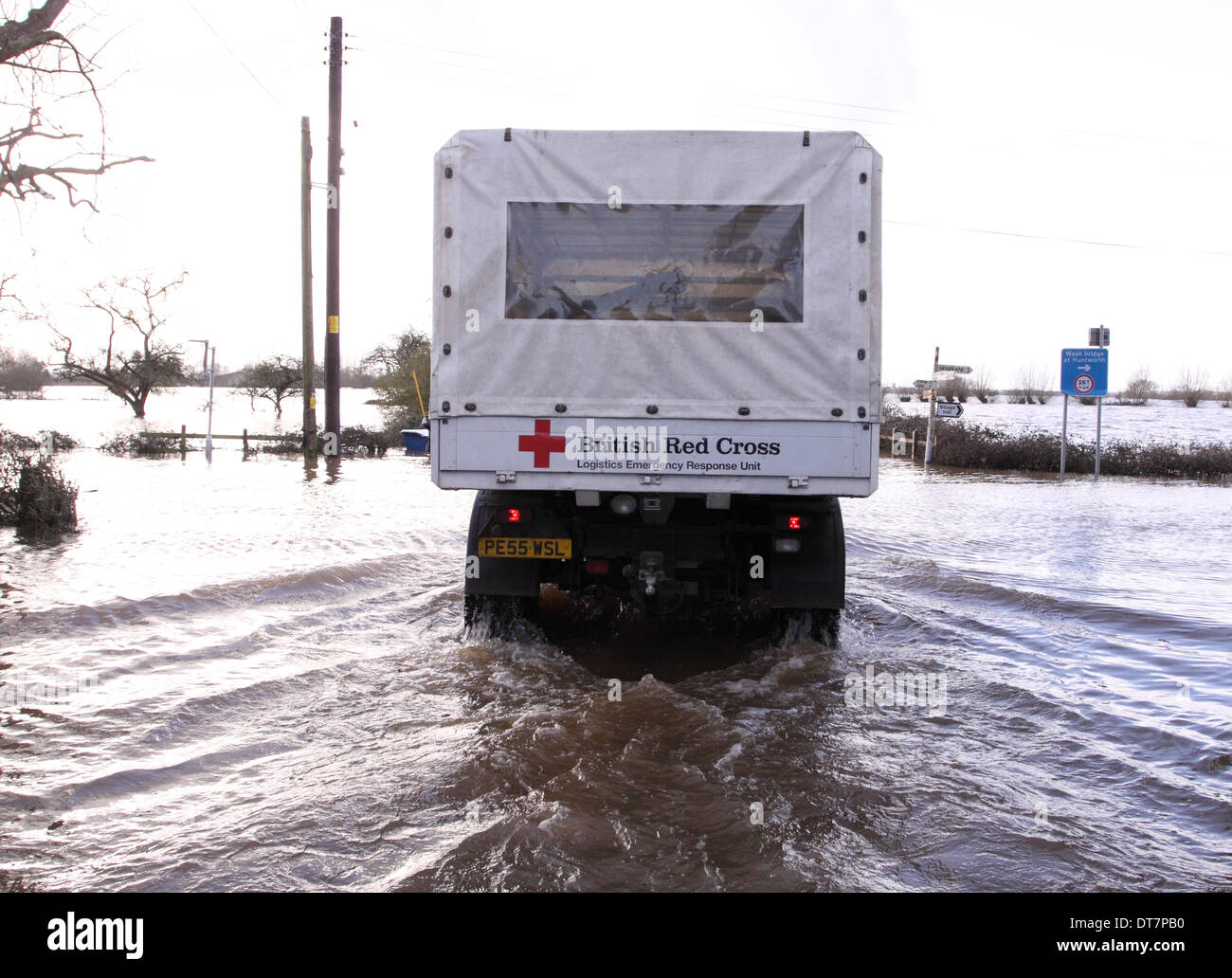 Burrowbridge, Somerset, Royaume-Uni - 11 février 2014. La Britsh Croix rouge, continuer à fournir des secours sur les niveaux de Somerset, le véhicule Unimog est présentée ici sur la A361 à Burrowbridge inondées. L'Unimog est équipé d'un tuba à l'échappement de route à travers l'eau d'inondation. Banque D'Images