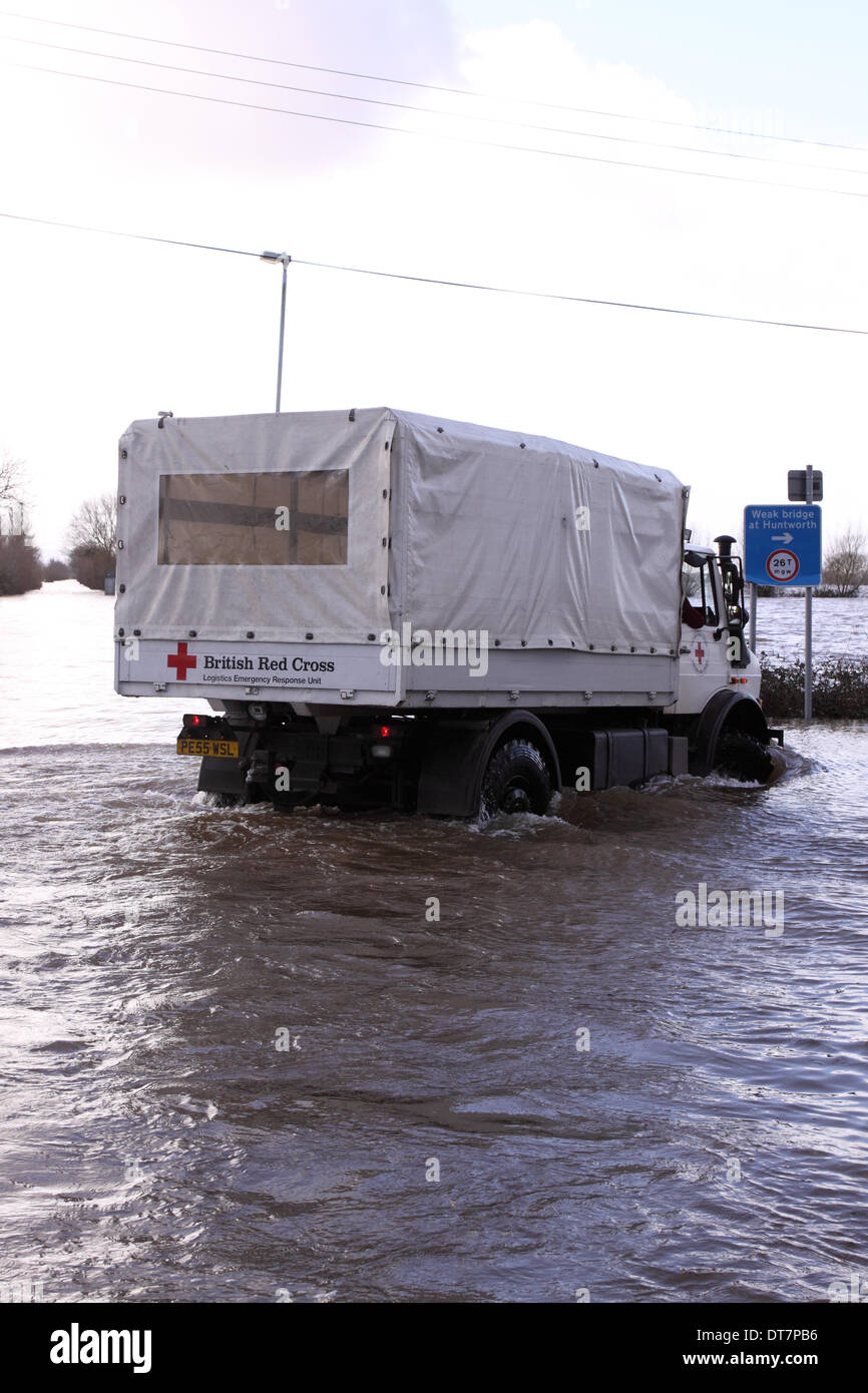 Burrowbridge, Somerset, Royaume-Uni - 11 février 2014. La Britsh Croix rouge, continuer à fournir des secours sur les niveaux de Somerset, le véhicule Unimog est présentée ici sur la A361 à Burrowbridge inondées. L'Unimog est équipé d'un tuba à l'échappement de route à travers l'eau d'inondation. Banque D'Images