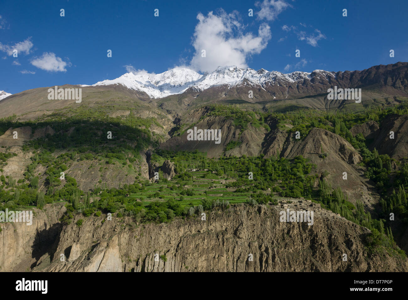 Village et de terrasses construites sur le flanc d'une vallée escarpée, avec les sommets enneigés du Rakaposhi derrière, vu de la route Karakoram entre la vallée de l'Hunza et Gilgit, Pakistan, Gilgit-Baltistan Banque D'Images