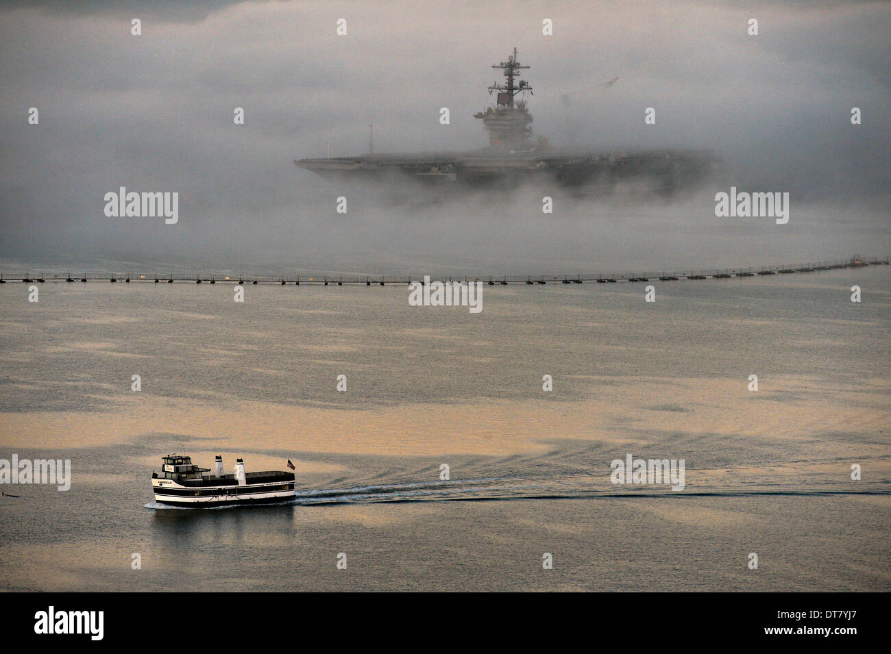 San Diego, CA, USA . Feb 11, 2014. Un laissez-passer de traversier de banlieue l'US Navy porte-avions nucléaire USS Ronald Reagan enveloppé dans le brouillard alors qu'elle s'assoit à son poste à quai, le 11 février 2014 à San Diego, CA. Credit : Planetpix/Alamy Live News Banque D'Images
