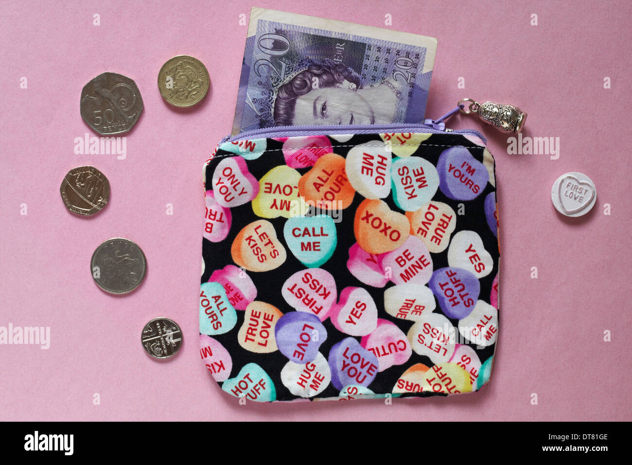 Amour coeur bourse avec £20 remarque, en pièces de monnaie et premier amour love heart sweet isolé sur fond rose Banque D'Images