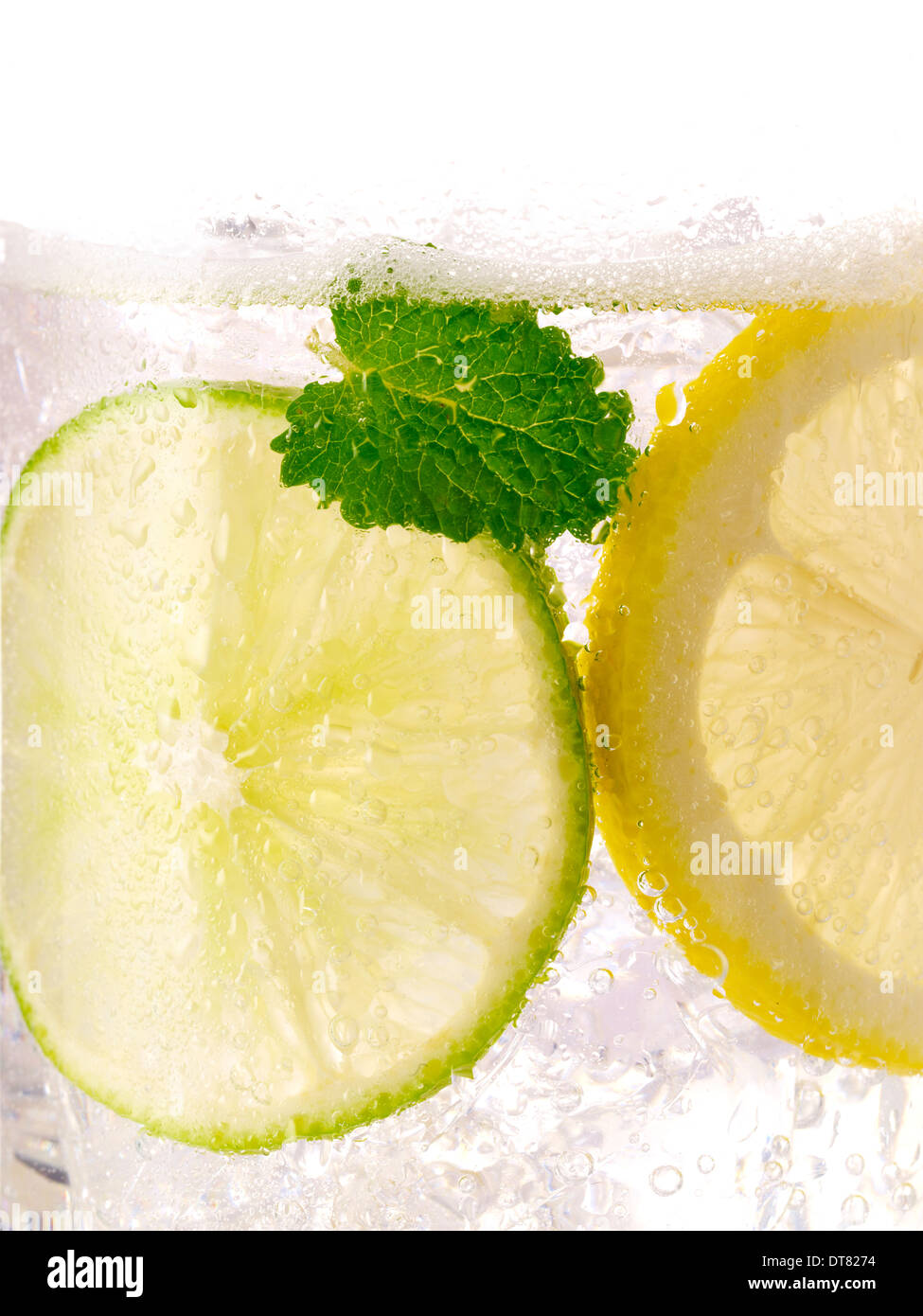 Un close up detail d'un citron lime avec une feuille de menthe avec de la glace dans un verre transparent Banque D'Images