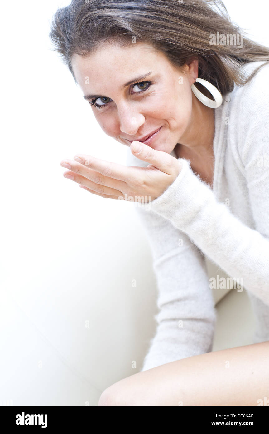 Jeune femme assise sur un canapé, riant (modèle récent) Banque D'Images