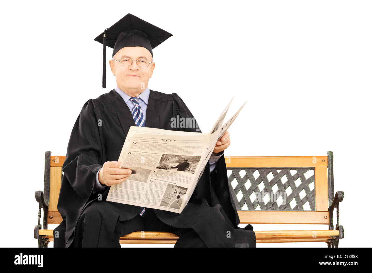 Man in graduation gown lire un journal assis sur un banc Banque D'Images