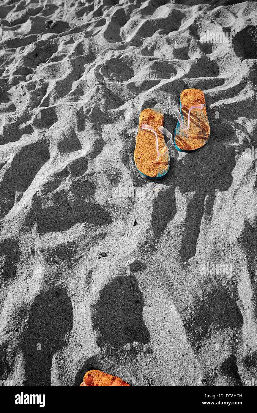 Flipflop sur la plage avec un orteil apparaissant au bas de la photo. Banque D'Images