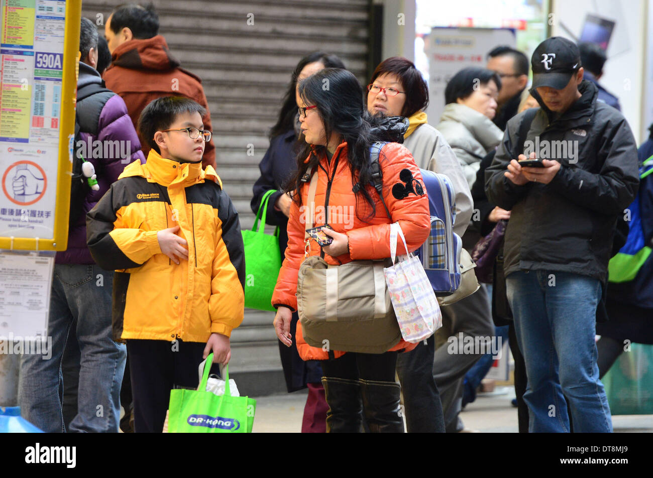 Hong Kong, Chine. 12 Février, 2014. Les citoyens de porter des vêtements épais attendre le bus à Hong Kong, Chine du sud, le 12 février 2014. Hong Kong a été frappé par un temps froid récemment avec la température la plus basse de frapper 7,3 degrés Celsius le mercredi, marquant ainsi un record depuis le mois de février 1996. © Qin Qing/Xinhua/Alamy Live News Banque D'Images