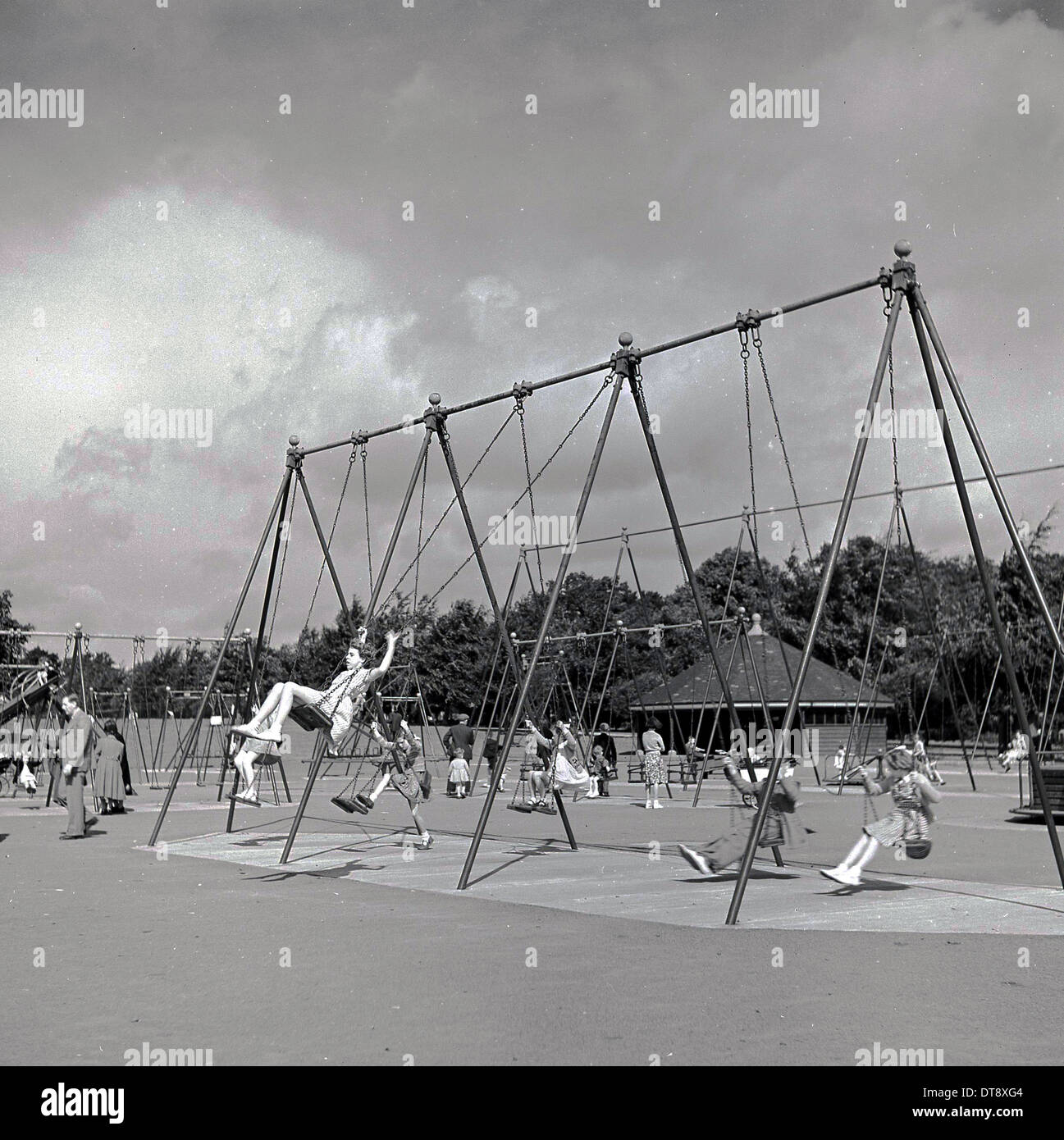 Photo historique de 1960 montrant les enfants de l'école profitant du type traditionnel des balançoires dans un terrain de jeux. Banque D'Images