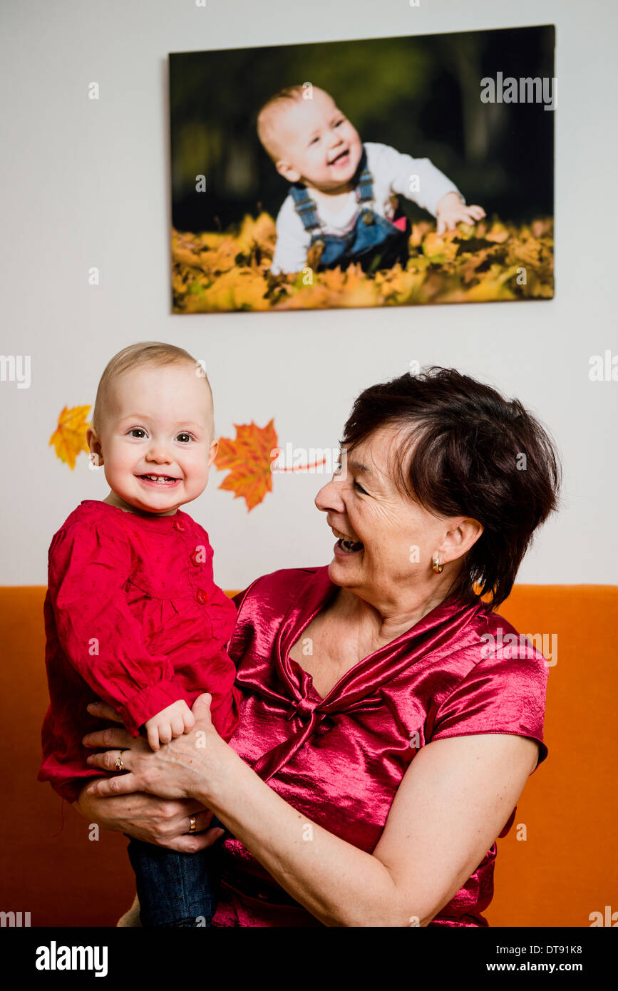 Portrait d'intérieur de grand-mère avec sa petite-fille - Photo de bébé sur le mur Banque D'Images